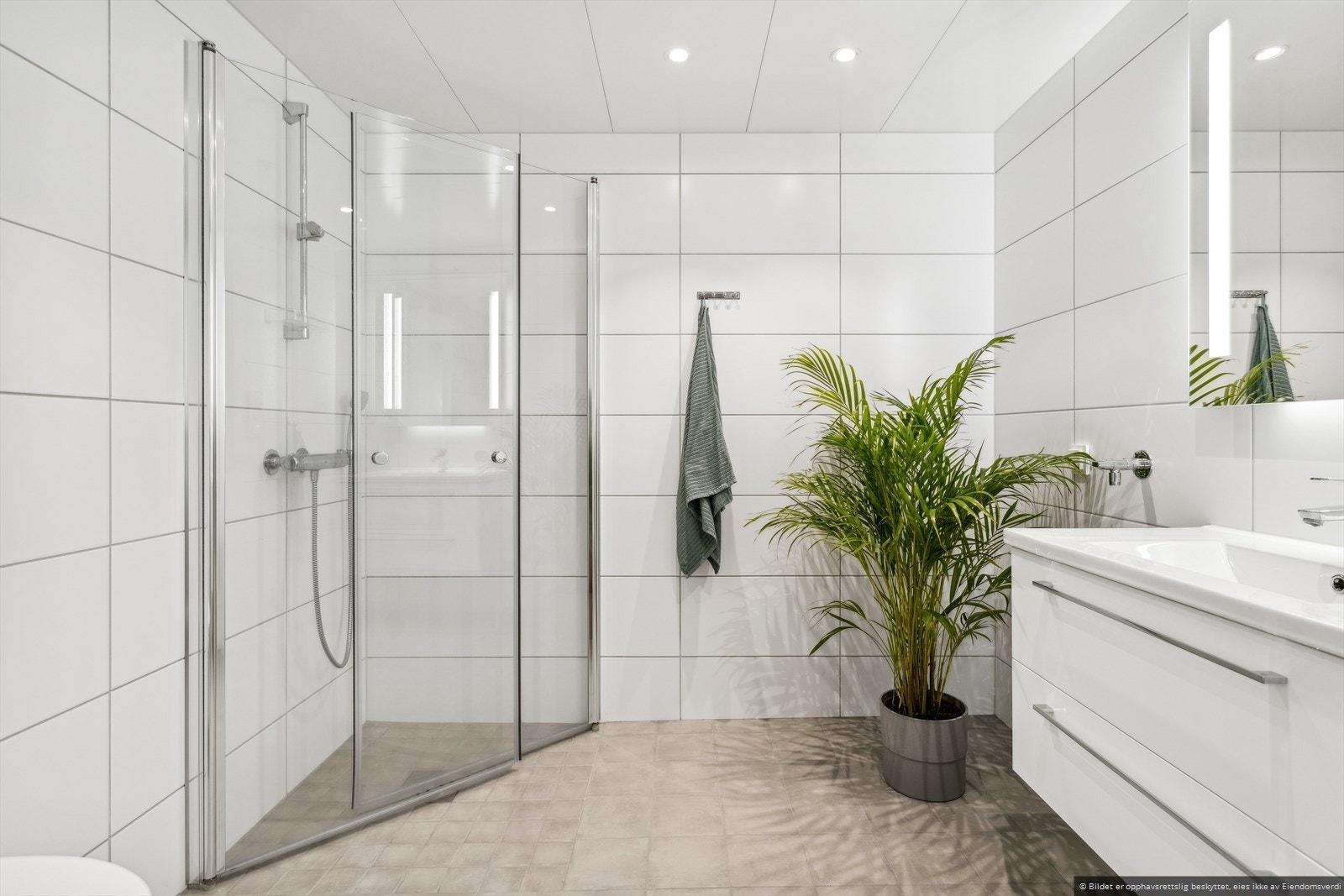 Badet er innredet i moderne stil og har behagelig gulvvarme, samt downlights elegant integrert i himlingen. I forbindelse med salget har takstmannen vurdert badet til å være i topp stand, med tilstandsgrad 0 på alle punkter. Galleribilde