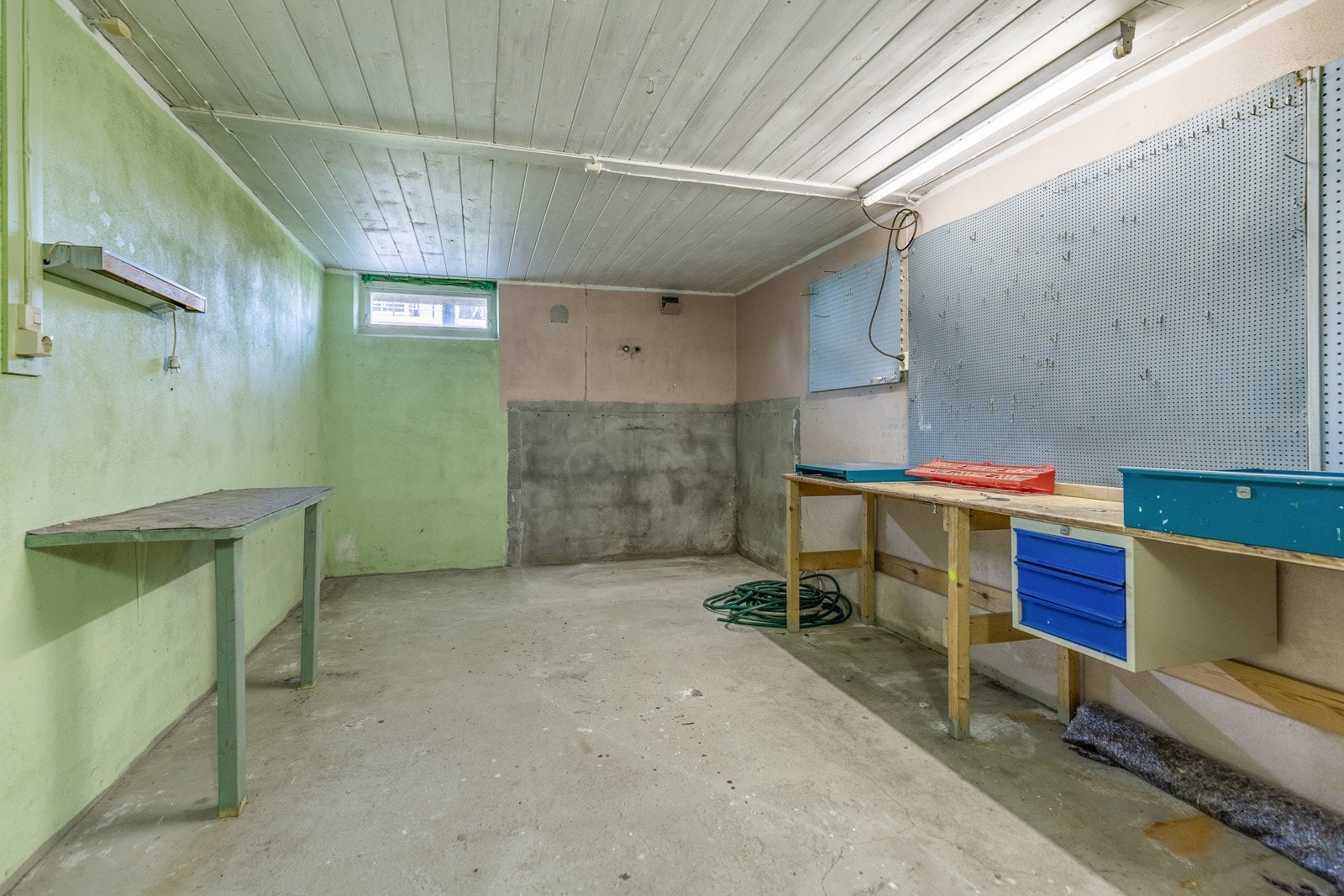 Romslig kjellerrom med arbeidsbenk, verktøytavle og god takhøyde. Galleribilde