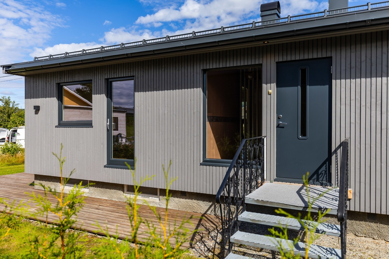 Gråmalt fasade med svart inngangsdør og vinduer. Galleribilde