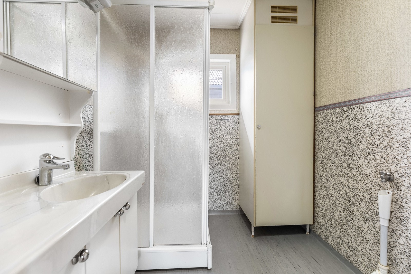 Badet har dusjkabinett, servant med underskap og et høyskap. Galleribilde