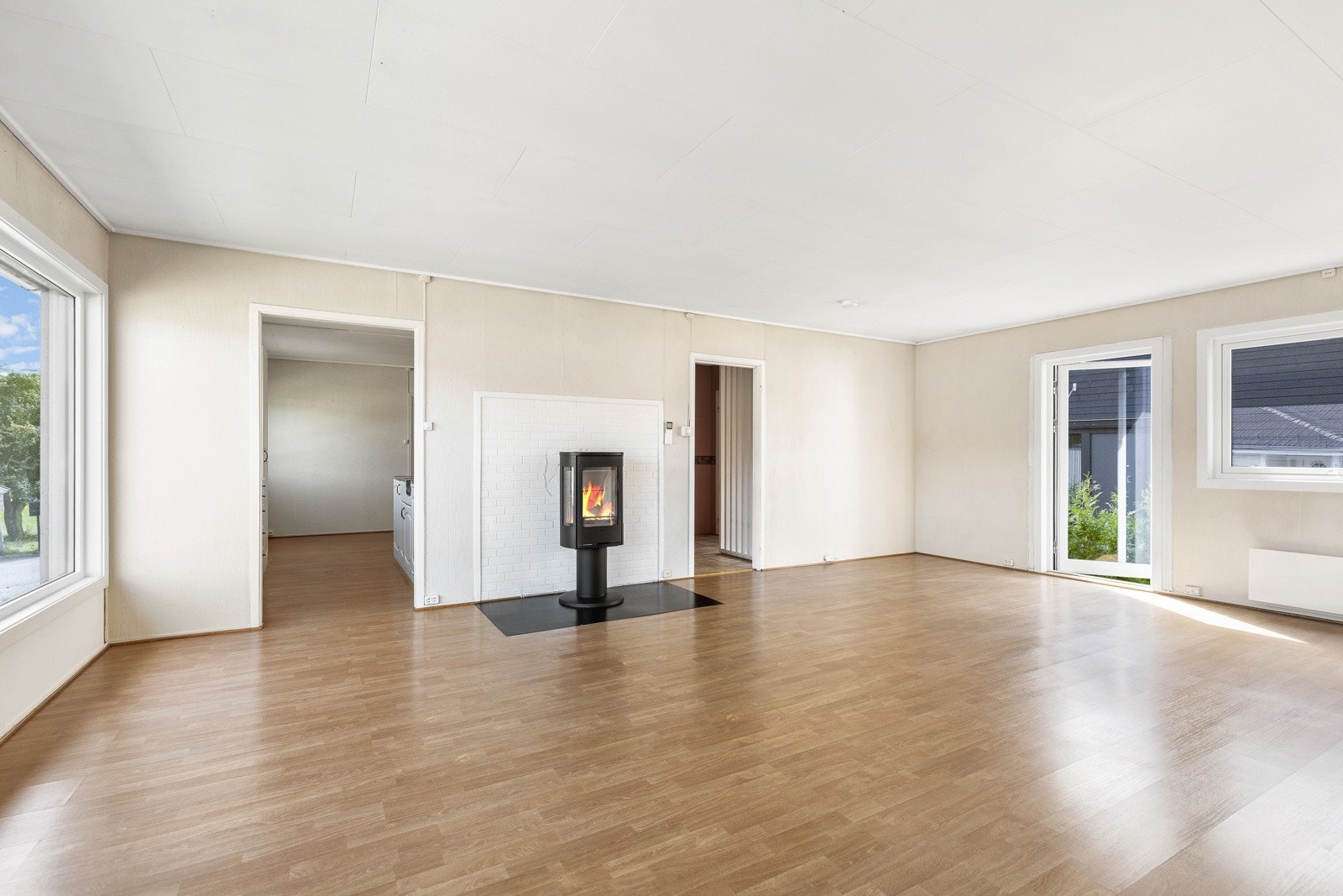 Romslig stue med peisovn, store vinduer og utgang til hage. Lys og luftig atmosfære med god plass. Galleribilde