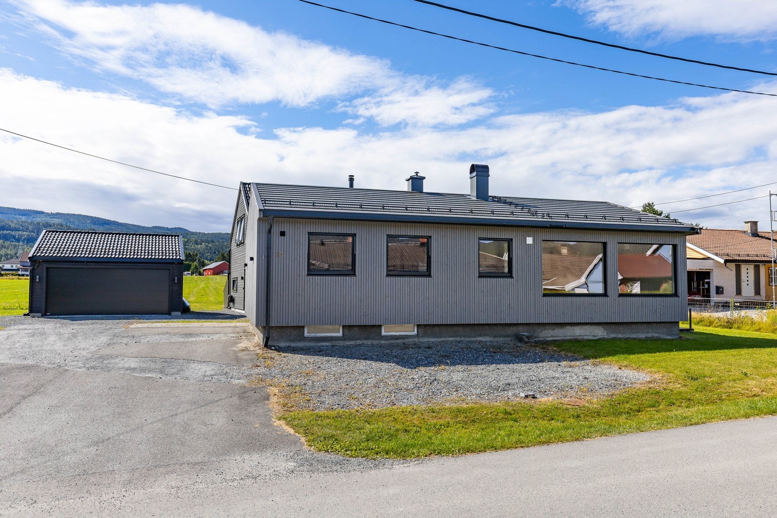 Boliger er beliggende i et landlig område med asfaltert oppkjørsel og grønn plen. Galleribilde