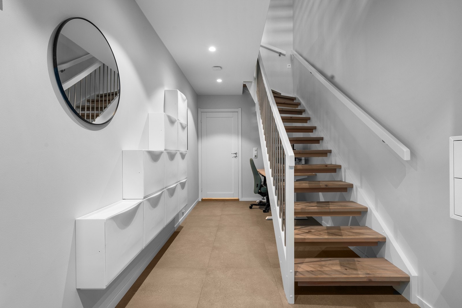 Den langstrakte gangen har downlights i himlingen og malt tretrapp til etasjene over. Galleribilde