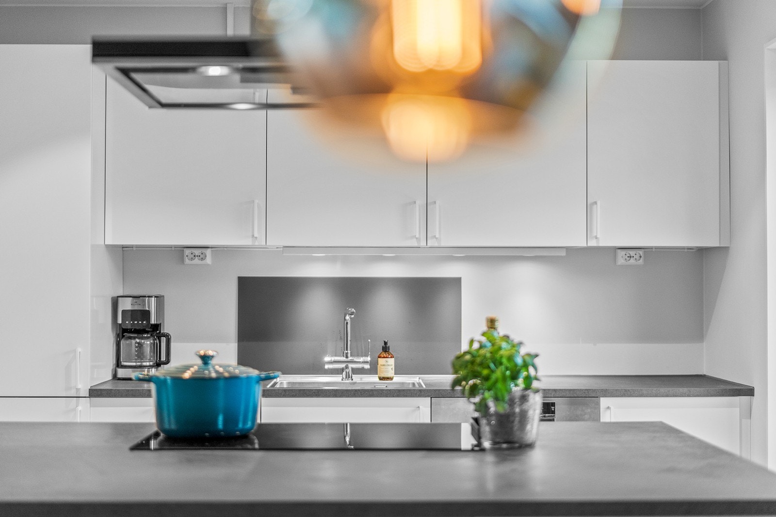 Innredningen har hvite, glatte fronter og laminatbenkeplate med planlimt kum i stål. Galleribilde