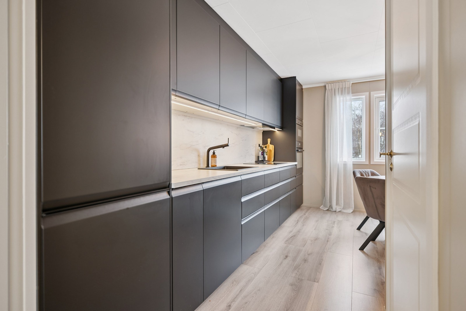 Den åpne løsningen mot stuen gjør kjøkkenet til en sosial del av leiligheten. Galleribilde