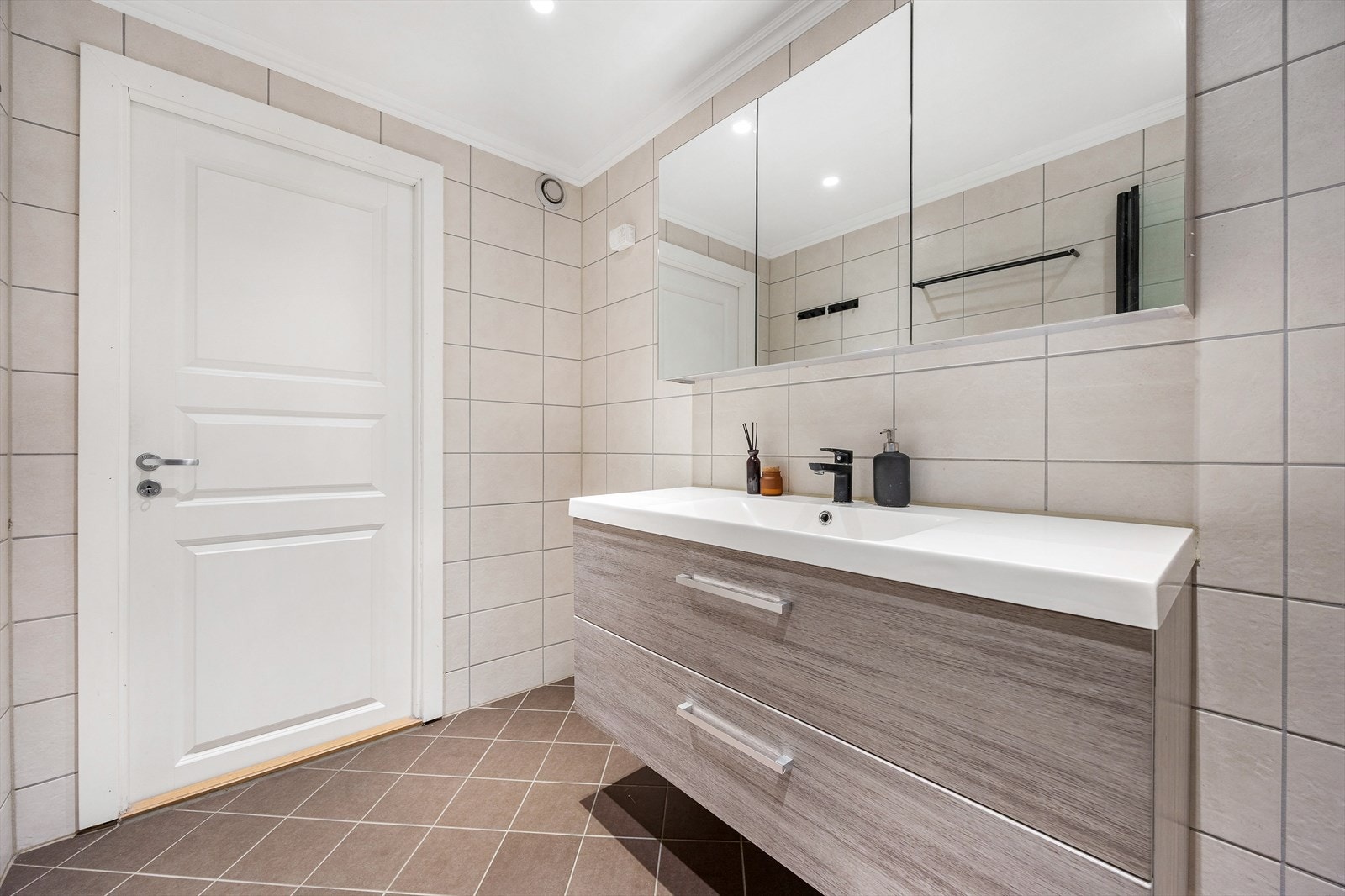 Badet er innredet med servantmøbel med glatte fronter og et stort speilskap. Det er varmekabler på gulvet. Galleribilde