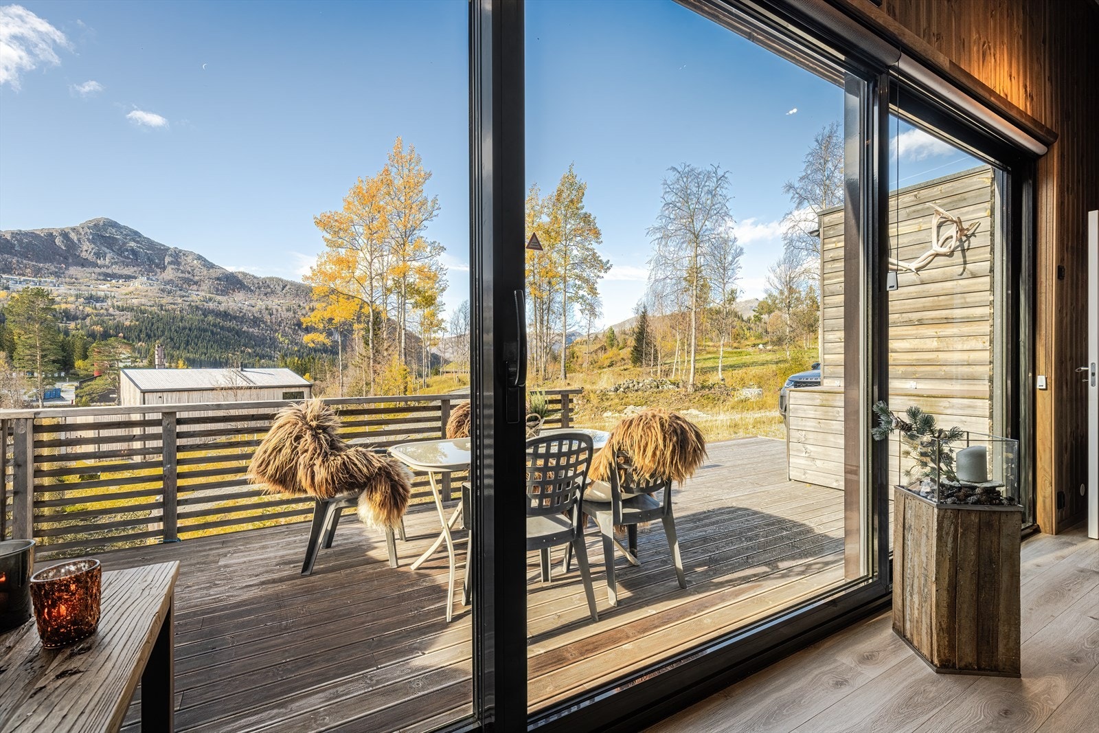 Fra oppholdsrommet er det store glassfasader med skyvedør ut til solrik terrasse. Galleribilde