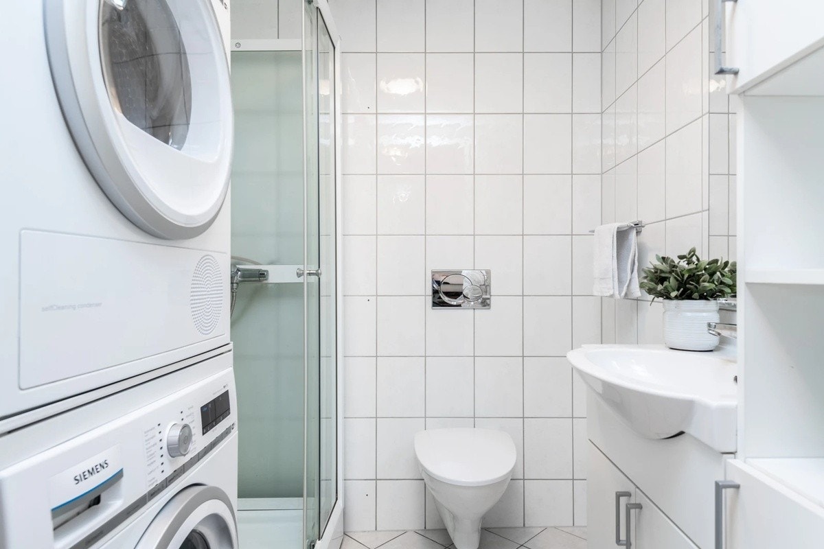 Bad med dusjhjørne, vaskemaskin og tørketrommel Galleribilde