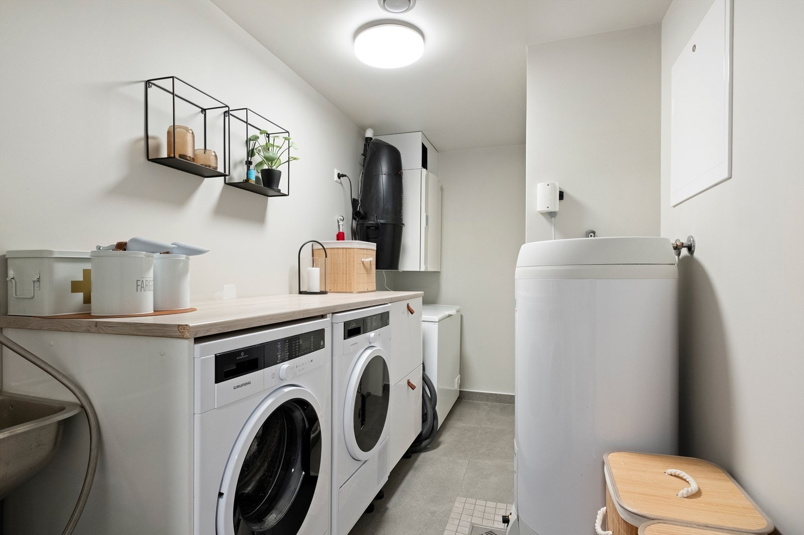 Vaskerommet er utstyrt med flislagt gulv og elektriske varmekabler. Det har balansert ventilasjon og inneholder varmtvannsbereder, vannfordelerskap, samt opplegg for vaskemaskin og tørketrommel. Her er også direkte utgang til carport. Galleribilde