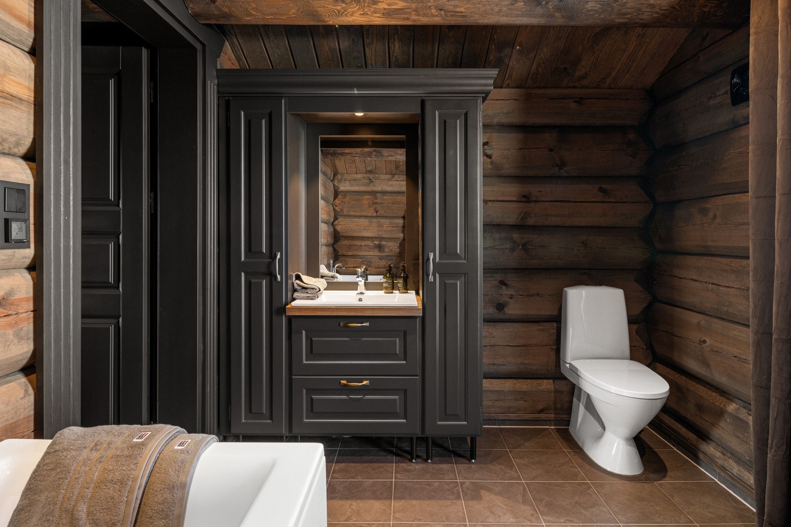 Stilrent bad med plassbygd innredning, god oppbevaring og et lunt uttrykk fra tømmerveggene. Galleribilde