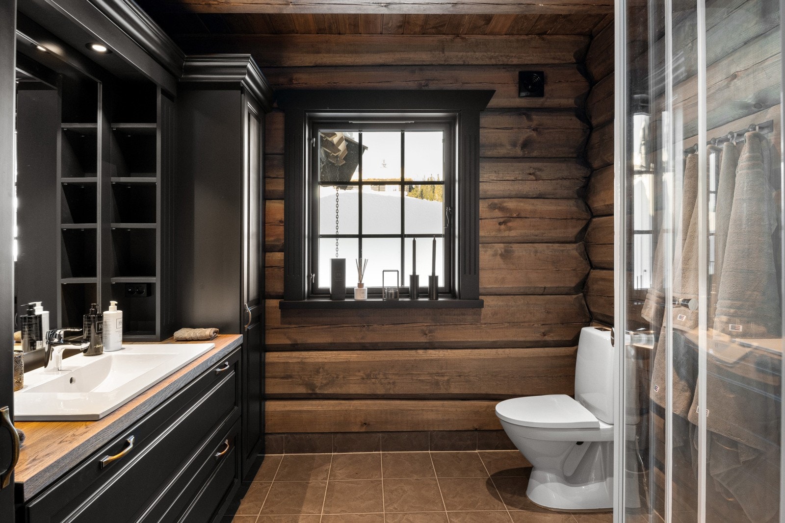 Et av hyttens delikate bad, flislagt, med dusjhjørne, moderne innredning og vindu som slipper inn naturlig lys. Galleribilde