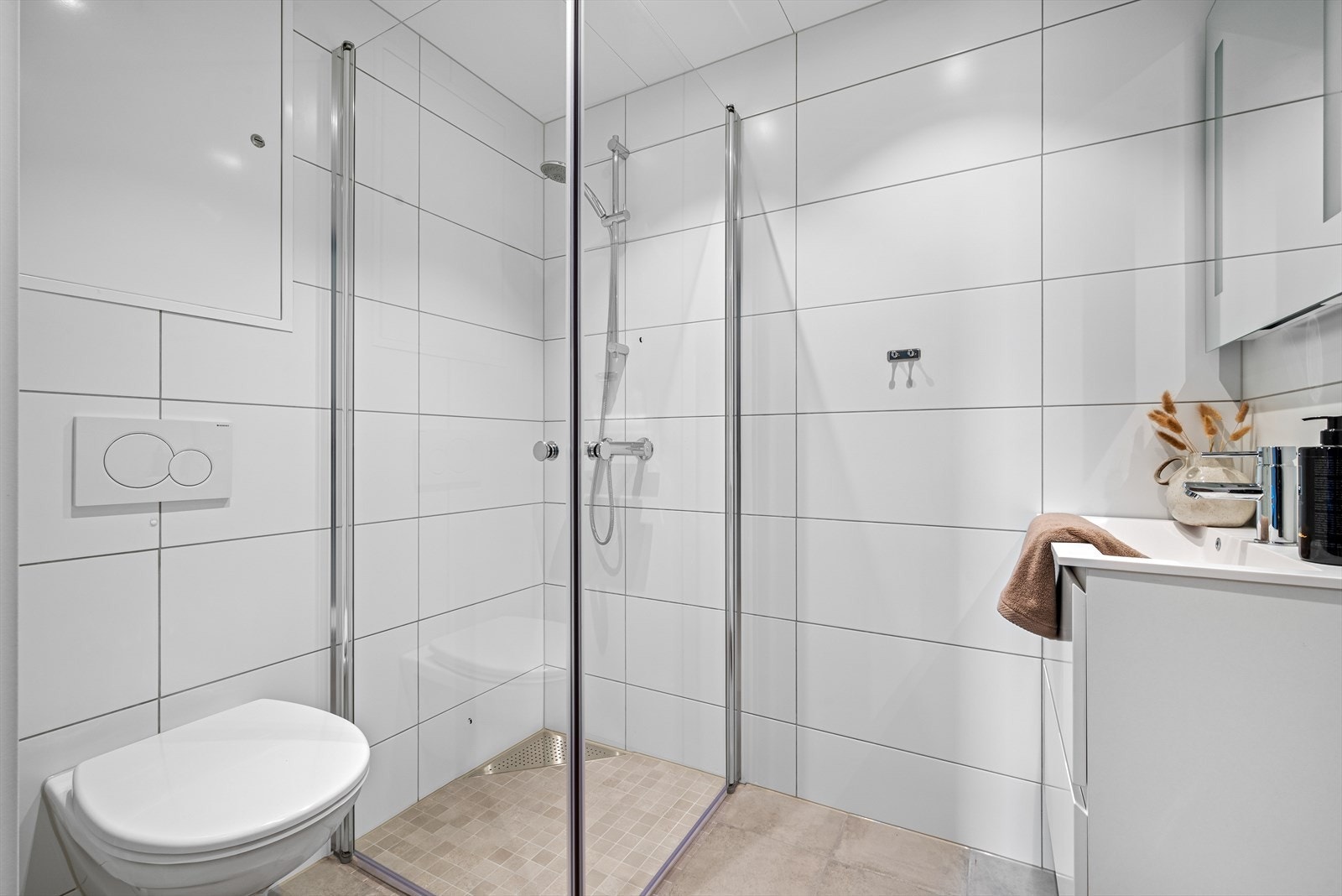 Her finner man bl.a. fliser på gulv, lekker baderomsinnredning med hvite profilerte fronter, vegghengt wc og opplegg for vaskemaskin. Galleribilde