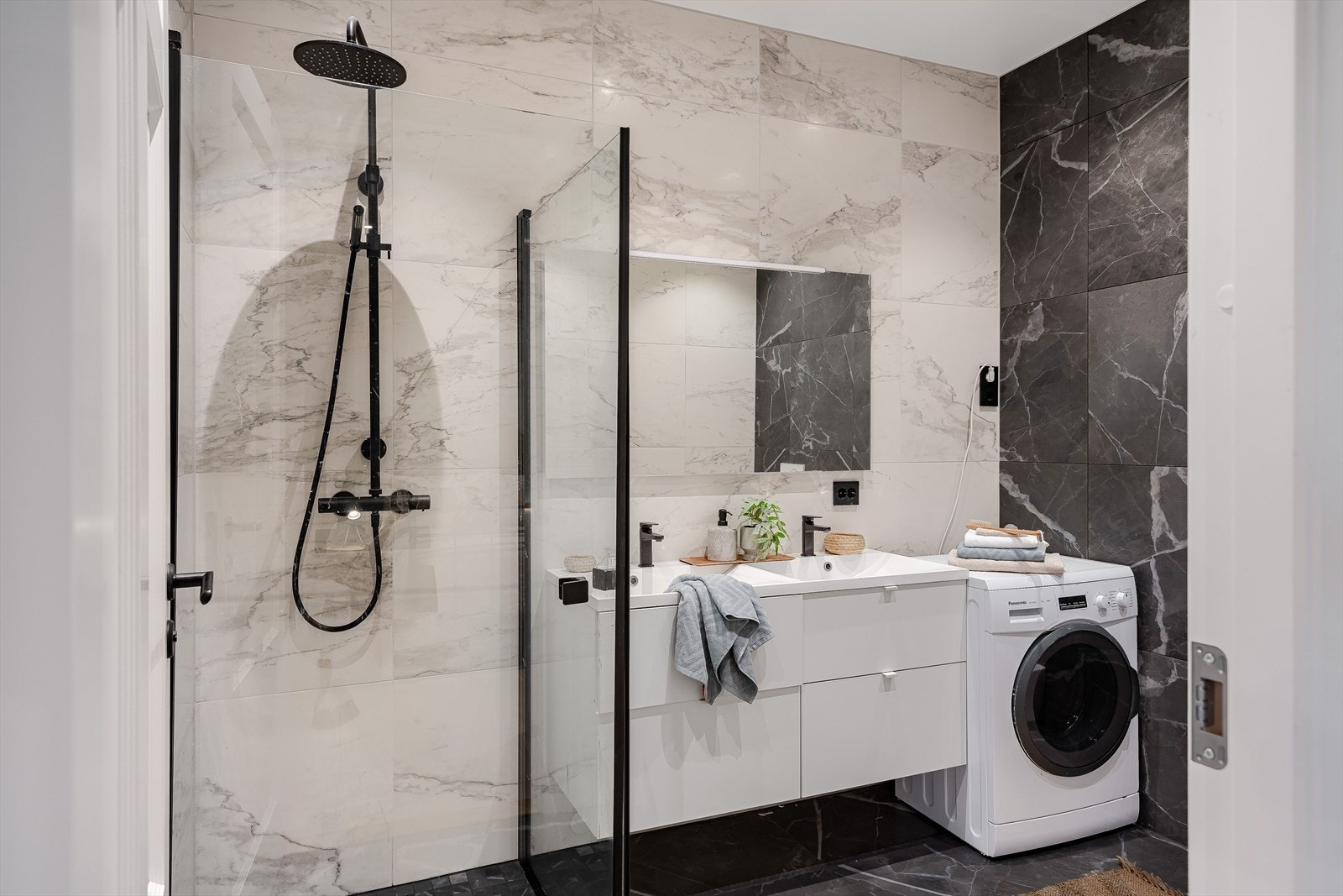 Lekkert og stilfullt bad med flislagte gulv og vegger. Badet er utstyrt dobbel baderomsinnredning med skuffer, opplegg for vaskemaskin og veggmontert toalett. Galleribilde