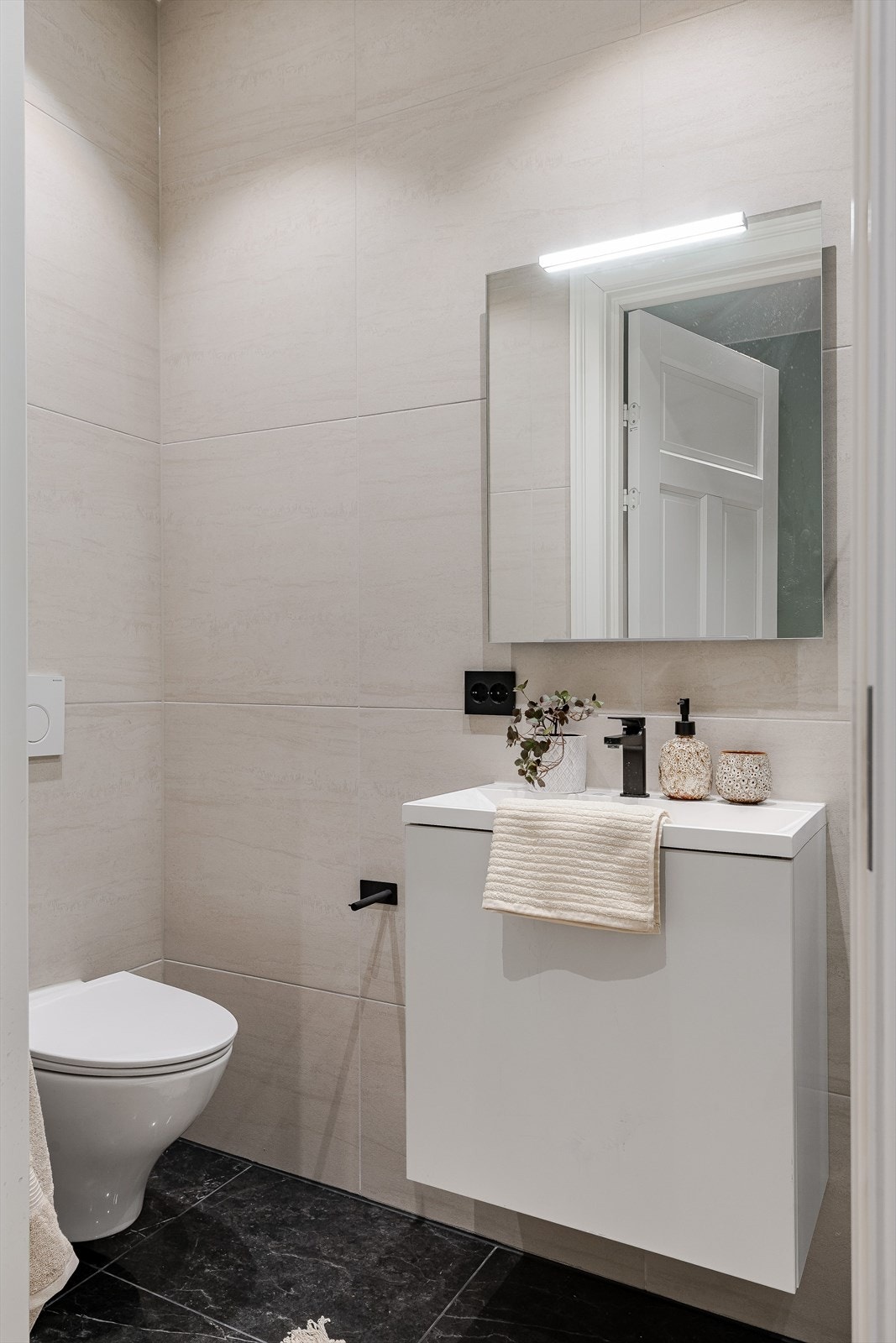 Leiligheten har to bad og dette er bad nummer to, med tilgang fra entréen. Rommet har flislagte vegger og gulv og er innredet med et vegghengttoalett og servantskap med heldekkende servant. Speil med lys og elektrisk uttak på vegg. Galleribilde