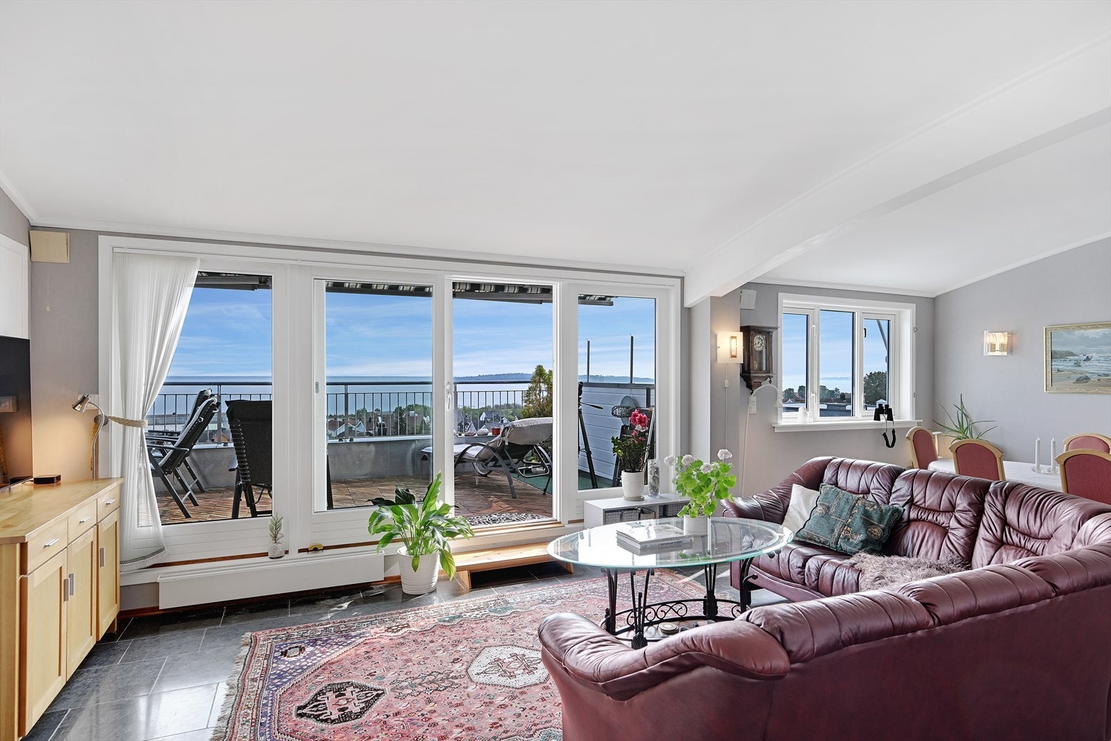 Stue med buet tak og store vindusflater mot takterrasse og utsikt. Galleribilde