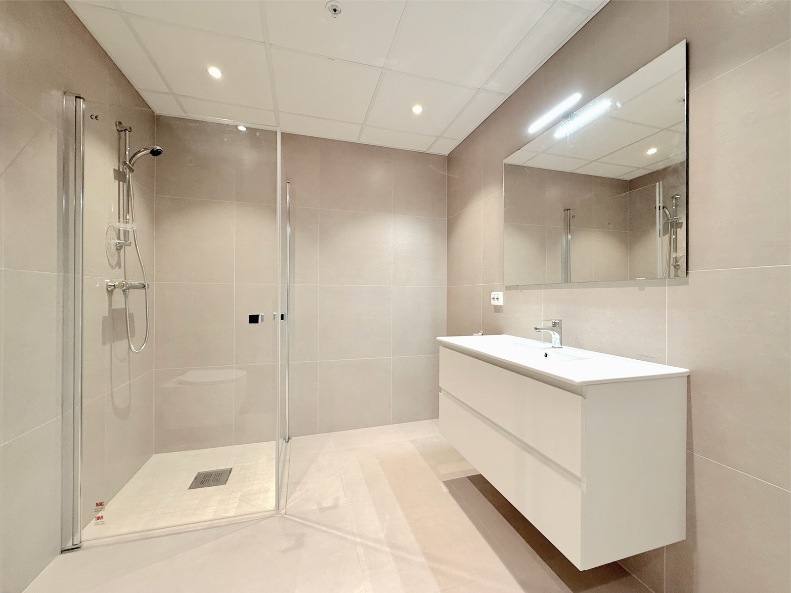 Delikat baderom med fliser, dusjhjørne og servantskap. Galleribilde