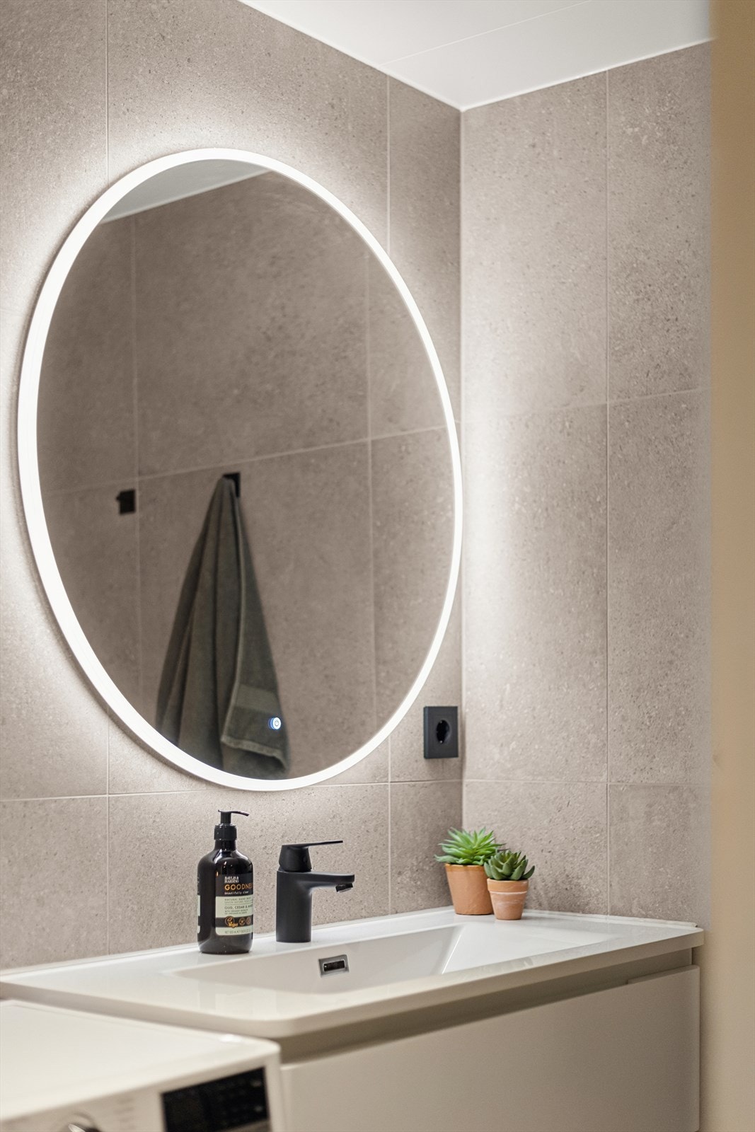 Badet er utstyrt med en servantinnredning med nedfelt servant, speil med lys, veggmontert toalett og et dusjhjørne med dusjvegger. Galleribilde