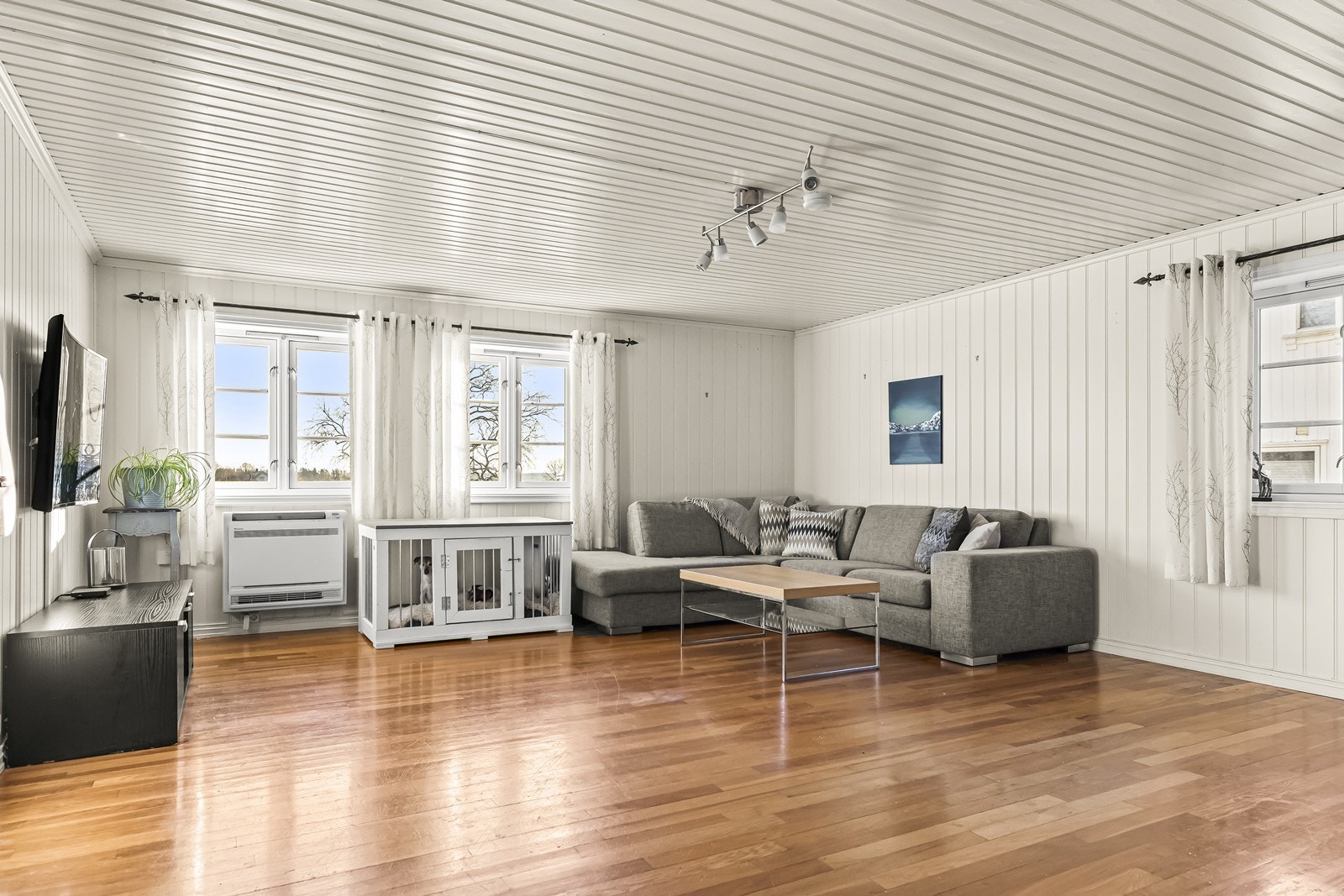 Stue med store vindusflater som gir godt lysinnslipp og utsyn mot hageområde. Galleribilde