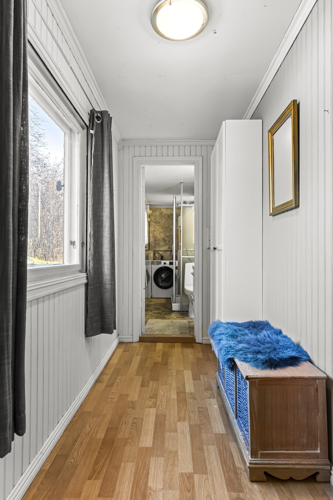 Laminatgulv og panelte vegger gir et klassisk uttrykk i entréen. Direkte tilgang til badet med dusjkabinett og vaskemaskinopplegg. Galleribilde