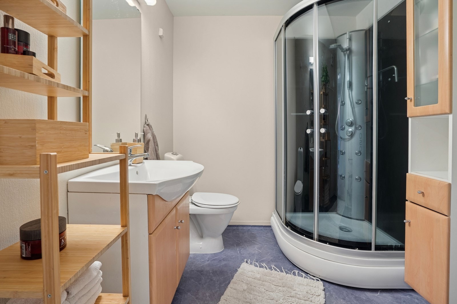 Lyst bad utstyrt med dusjkabinett, gulvstående wc og baderomsinnredning. Galleribilde