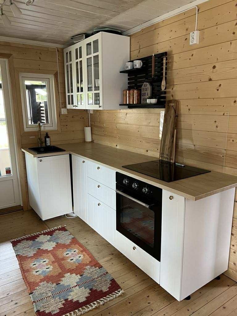 Oppbevaringsplass i over- og underskap. Utstyrt med integrert komfyr med platetopp, samt frittstående kjøl-/fryseskap. Galleribilde