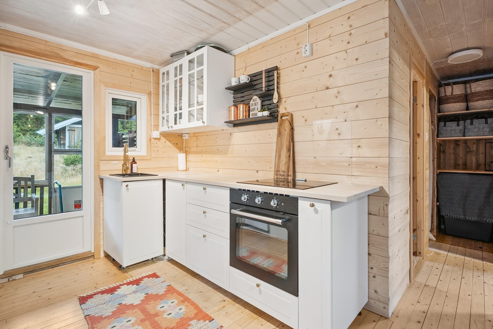 Lyst og nyere kjøkken fra IKEA med innredning i laminerte skrog og profilerte fronter. Benkeplate av laminat med nedfelt kjøkkenkum og glassplate bak. Galleribilde