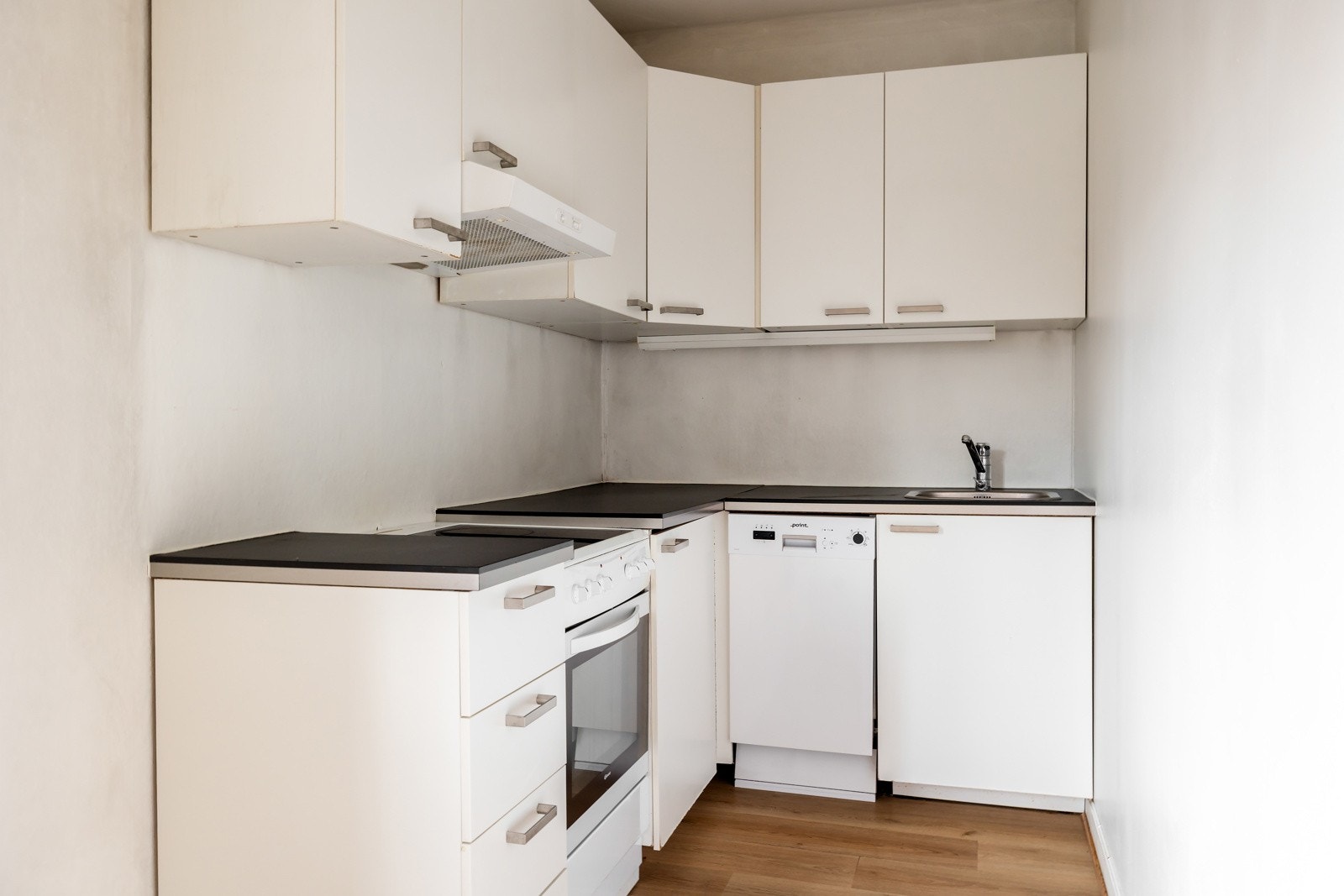 Kjøkkeninnredningen har glatte hvite fronter og benkeplate i laminat Galleribilde