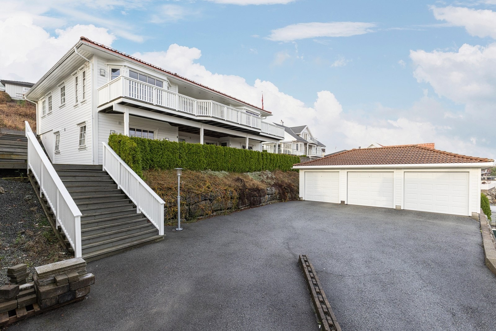 AnneTomten er meget pent opparbeidet med plen og variert beplantning. Asfaltert gårdsplass med biloppstillingsplasser og trippel garasje. Fra parkeringsområde er det trapper opp til utearealer og boligens inngangsparti. Galleribilde