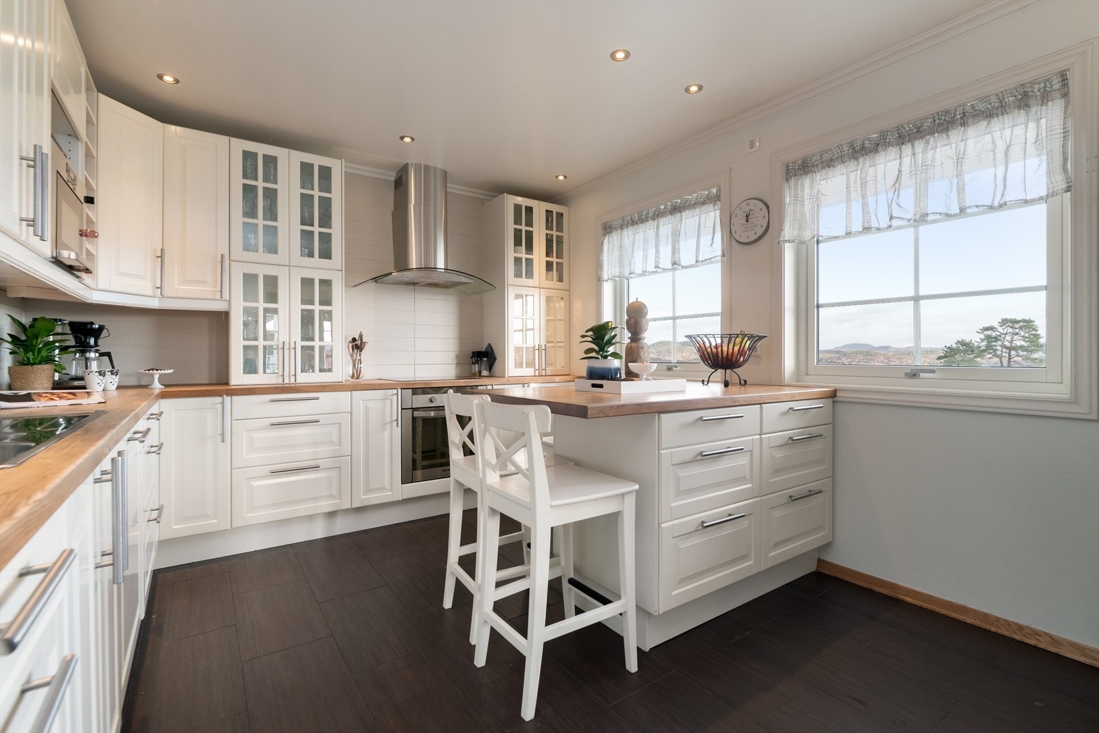 Kjøkkenet har innredning med profilerte fronter og benkeplate av heltre. Det er integrert oppvaskmaskin, induksjonstopp og stekeovn. Over stekesone er det ventilator med avtrekk ut. Galleribilde