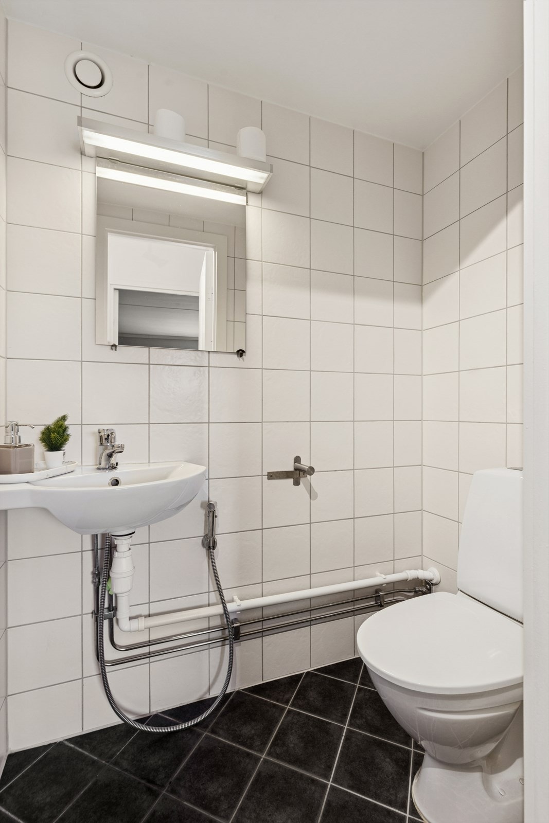 Separat toalettrom fra 2011 med flislate gulv- og veggflater. Rommet er utstyrt med gulvstående toalett og vegghengt vask. Galleribilde