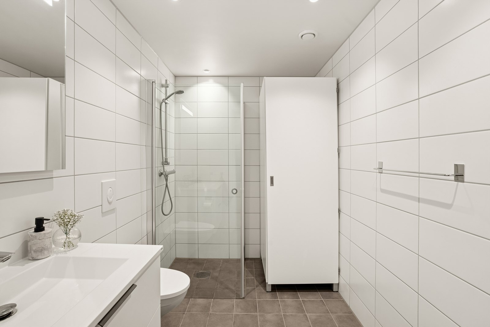 Baderommet er tidløst innredet med grå fliser på gulvet og hvite fliser på vegg. I gulvet har man også vannbåren varme for ekstra komfort. Galleribilde