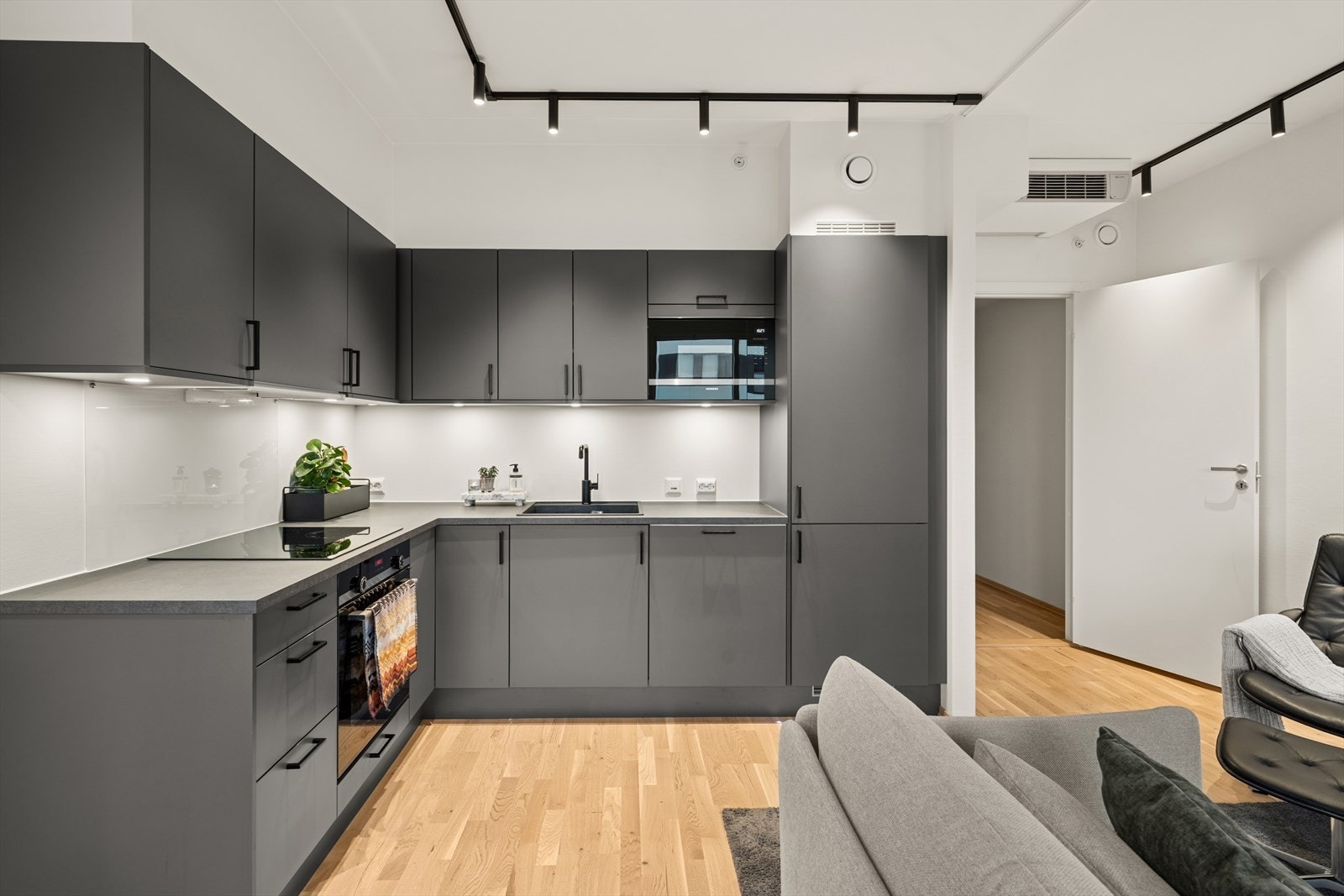 Kjøkkenet er lekkert innredet med grå, slette fronter med sorte detaljer og grå benkeplate i laminat. Her har man godt med skap og skuffeplass. Kjøkkenet er ellers godt utstyrt med integrerte hvitevarer. Galleribilde