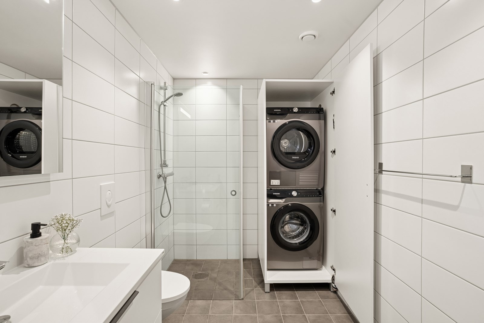 Badet er ellers utstyrt med dusjhjørne, vegghengt toalett og baderomsinnredning med nedfelt servant. I tillegg har man en praktisk skapløsning hvor man har plass til både vaskemaskin og tørketrommel. Galleribilde