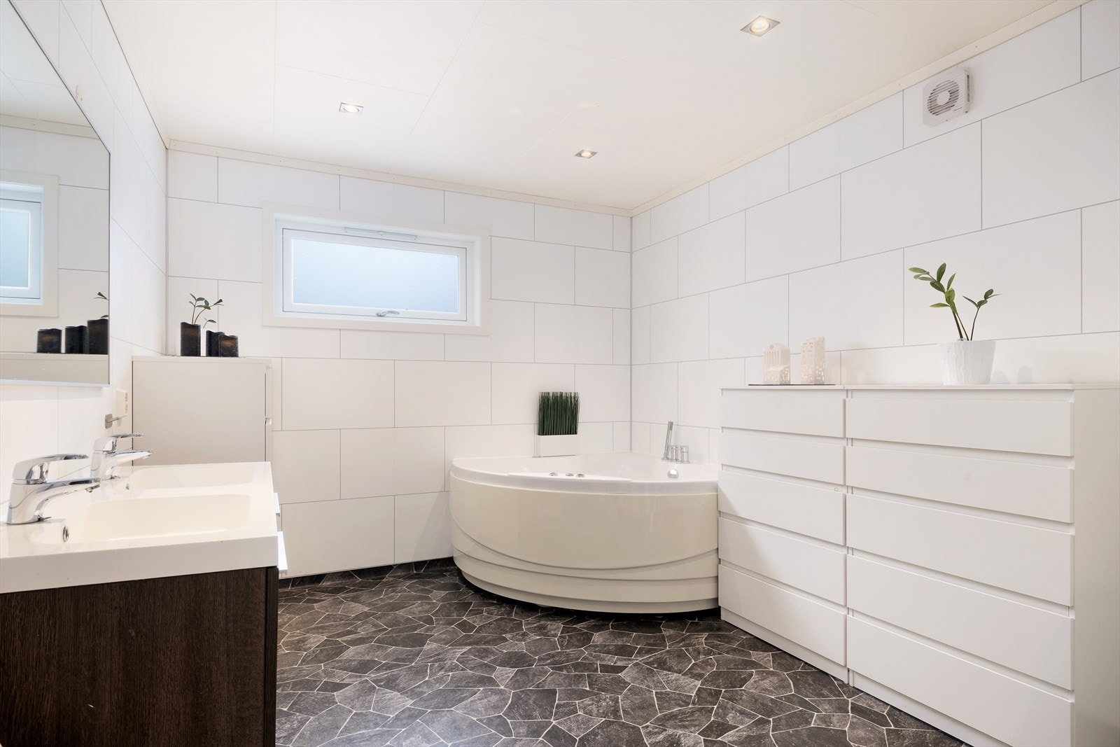 Badet er av god storleik med våtromsbelegg på golv og våtromsplater på veggar. I taket er det måla takplater. Galleribilde