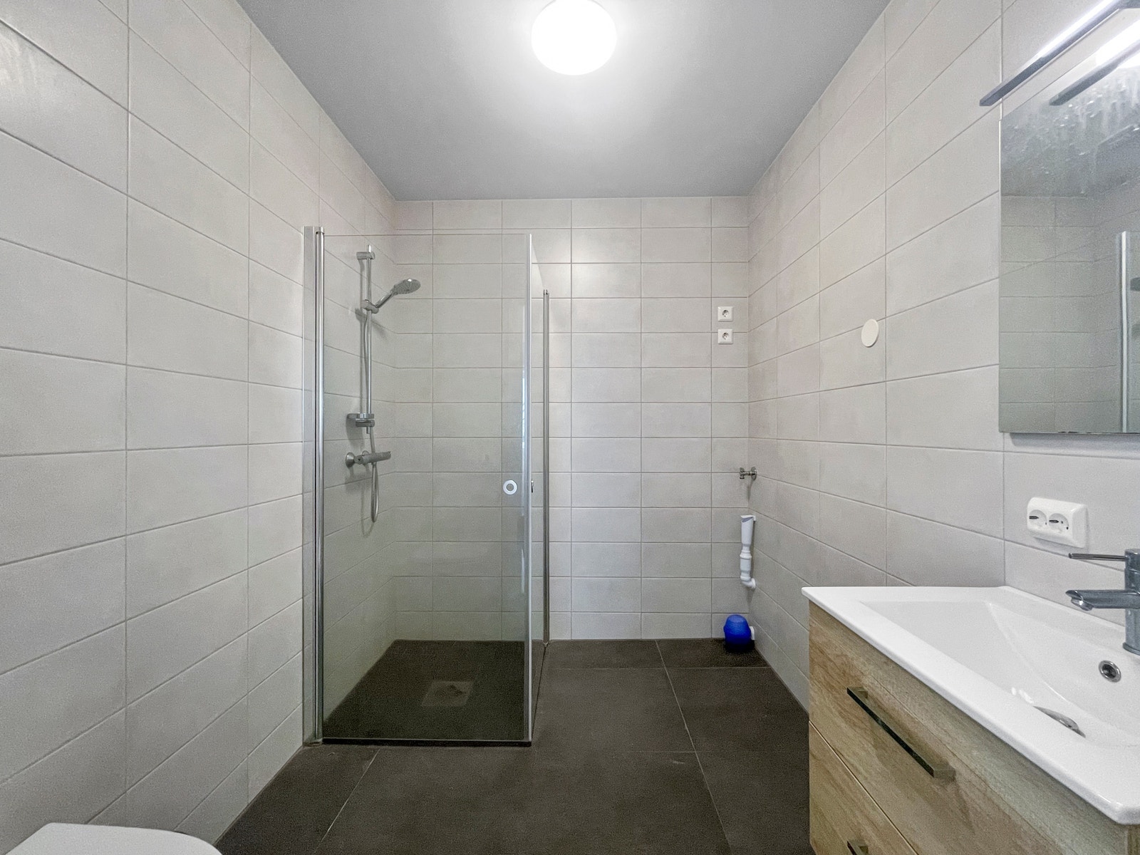 På badet er det et stort dusjhjørne, servant med underskap, vegghengt toalett, samt opplegg til vaskemaskin. Galleribilde