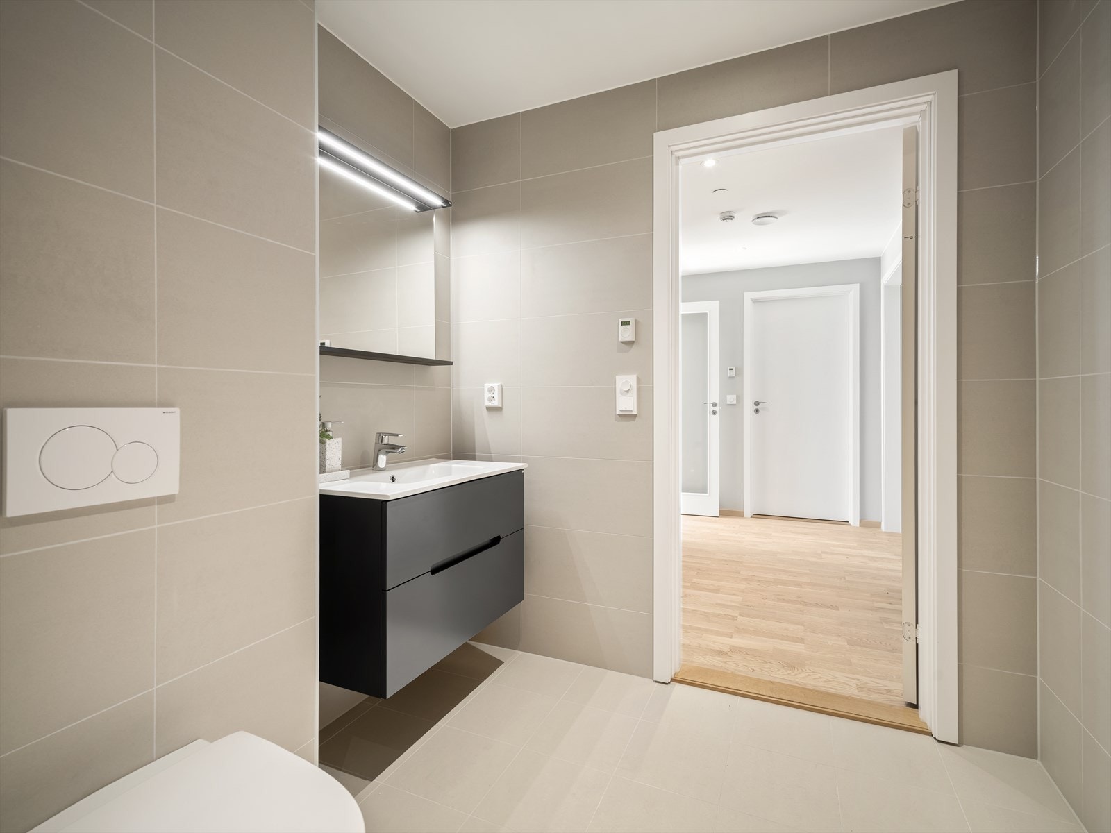 Lyst og lekkert bad med beige fliser i store formater Galleribilde