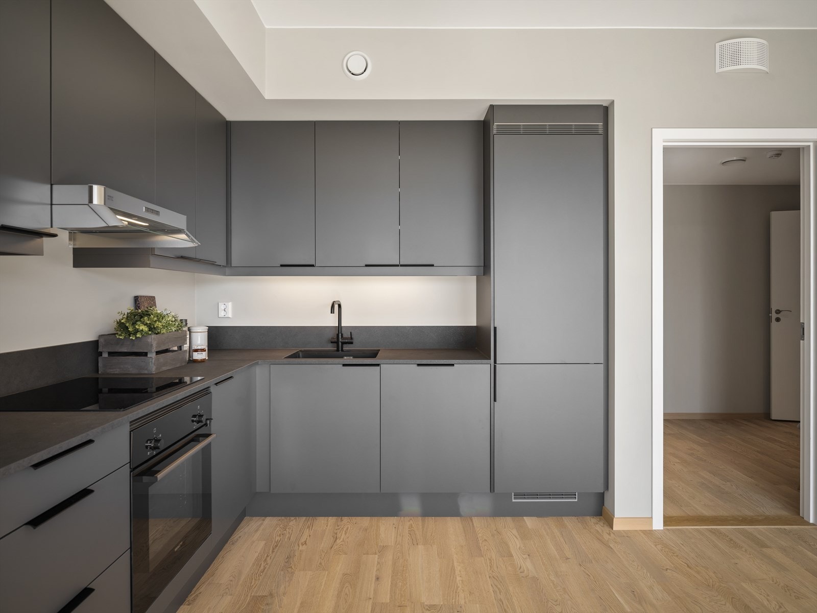 Kjøkkeninnredning med takhøye skap og integrerte hvitevarer Galleribilde