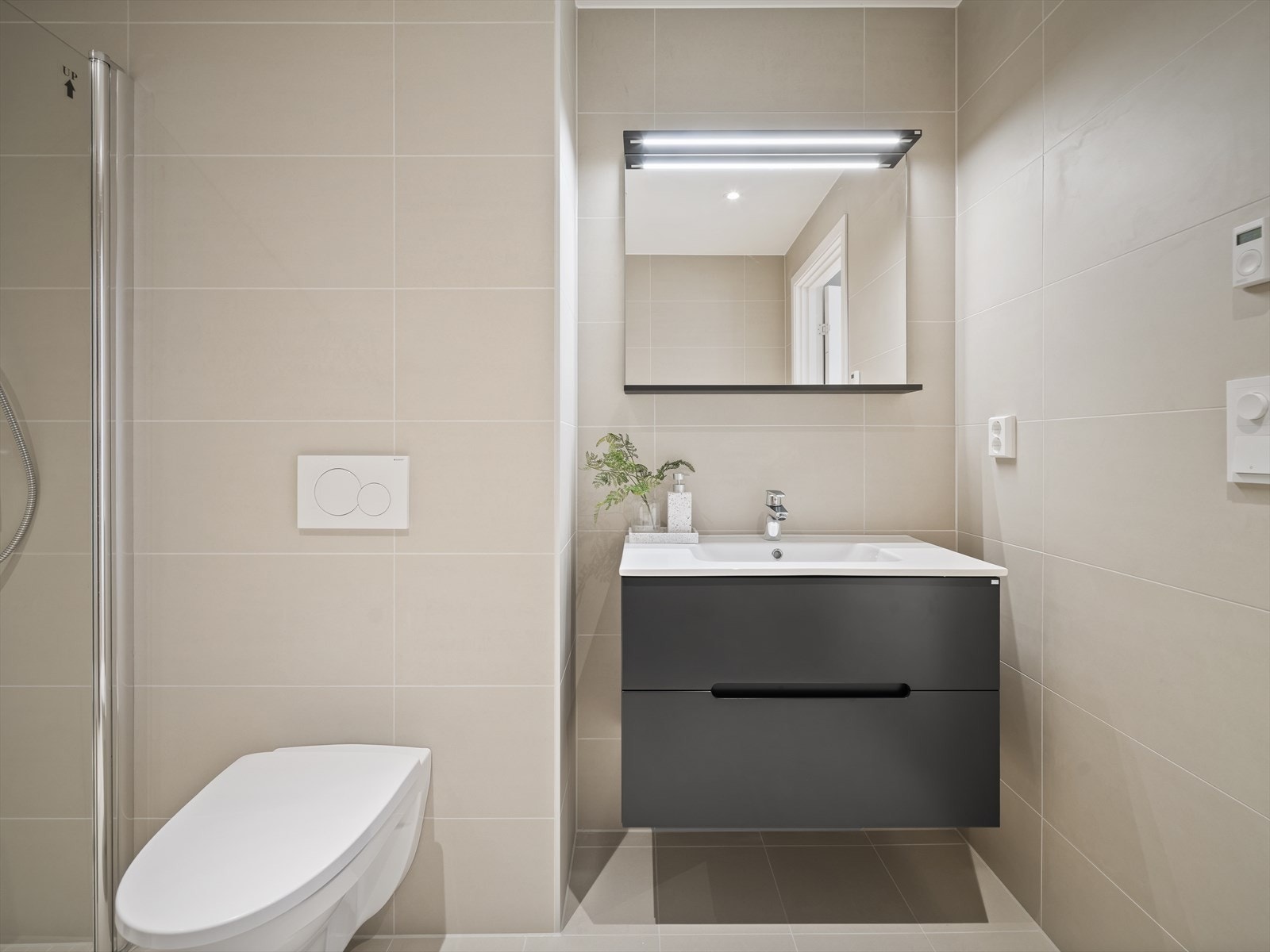 Lyst og lekkert bad med beige fliser i store formater Galleribilde