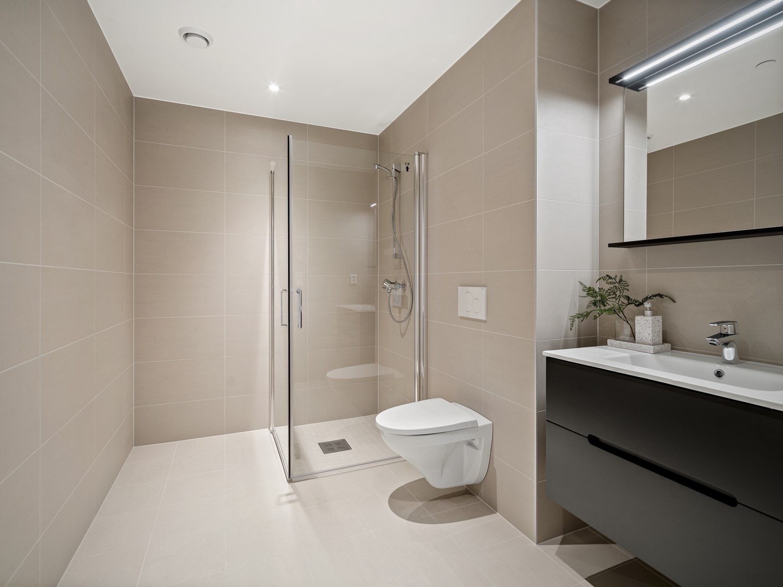 Lyst og lekkert bad med beige fliser i store formater Galleribilde