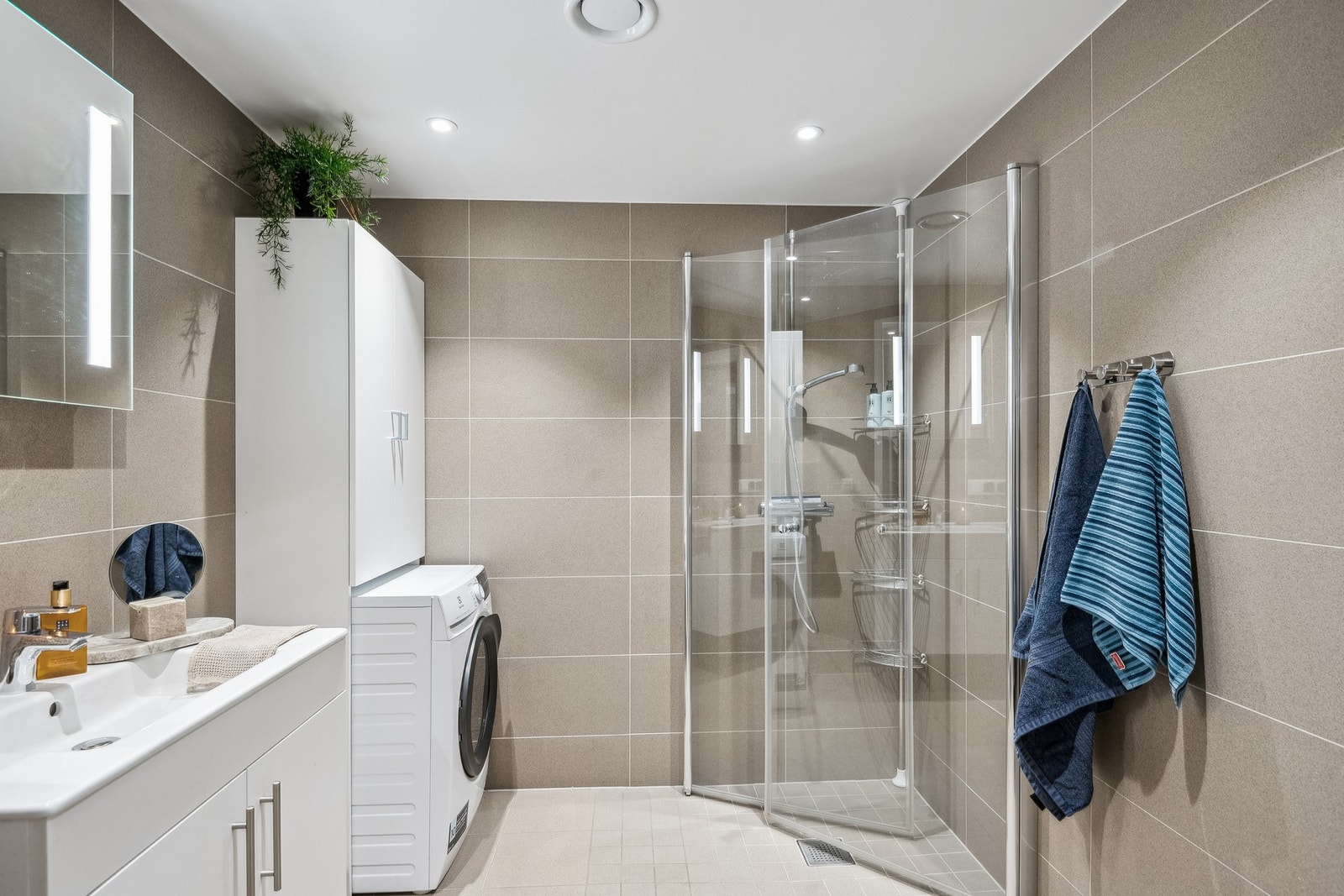 Videre finner du et baderom tilknyttet gangen som byr på flislagte vegger og gulv med gulvvarme, en vegghengt servantinnredning med heldekkende servant og en dusjnisje med innfellbare glassdører. Galleribilde