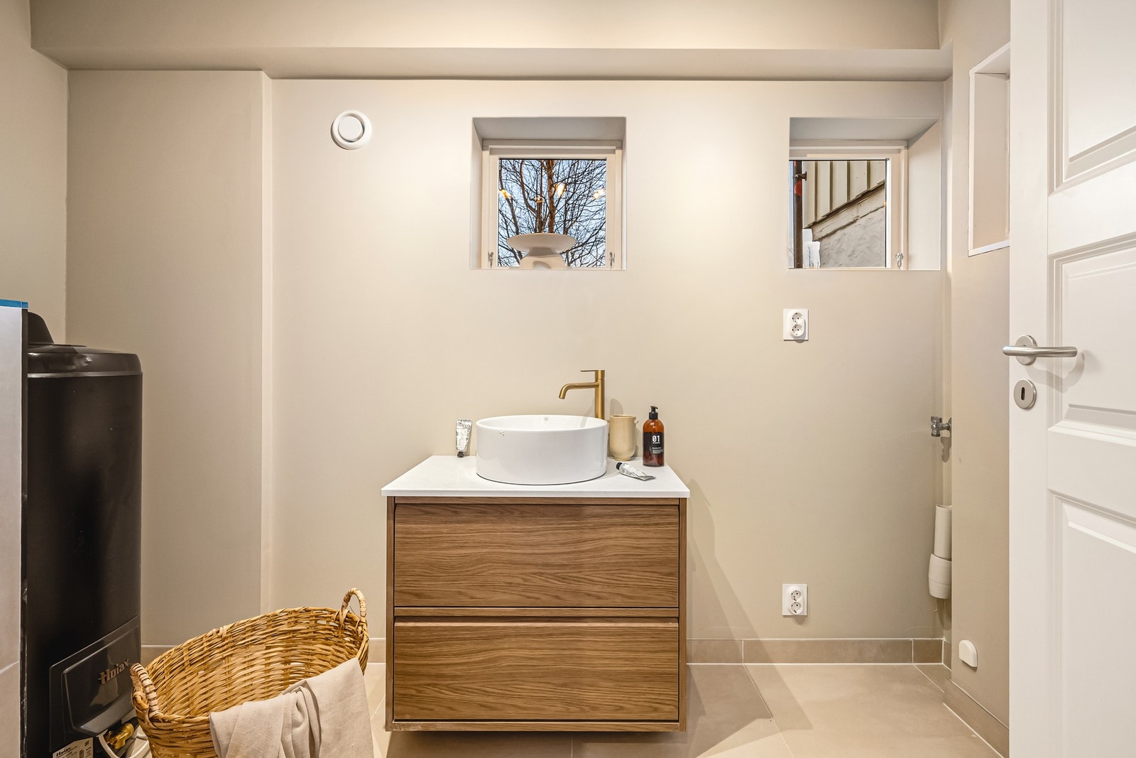 Vaskerommet inneholder vegghengt toalett, helstøpt servant, opplegg for vaskemaskin og varmtvannsbereder. Galleribilde