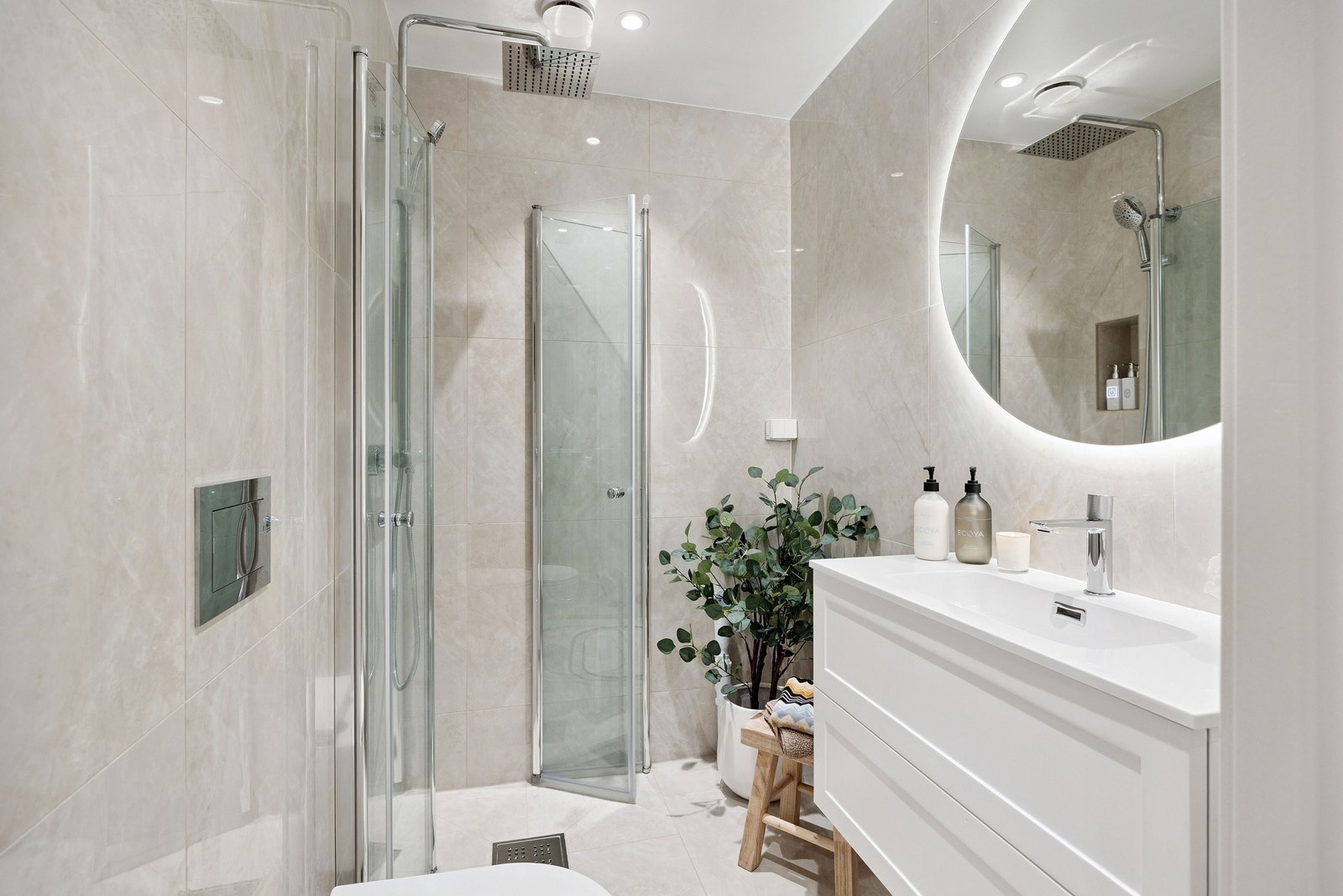 Badet har lekre beige fliser og et lyst, tidløst design. Foldedører på dusj for bedre plass og det er opplegg til vaskemaskin. Galleribilde