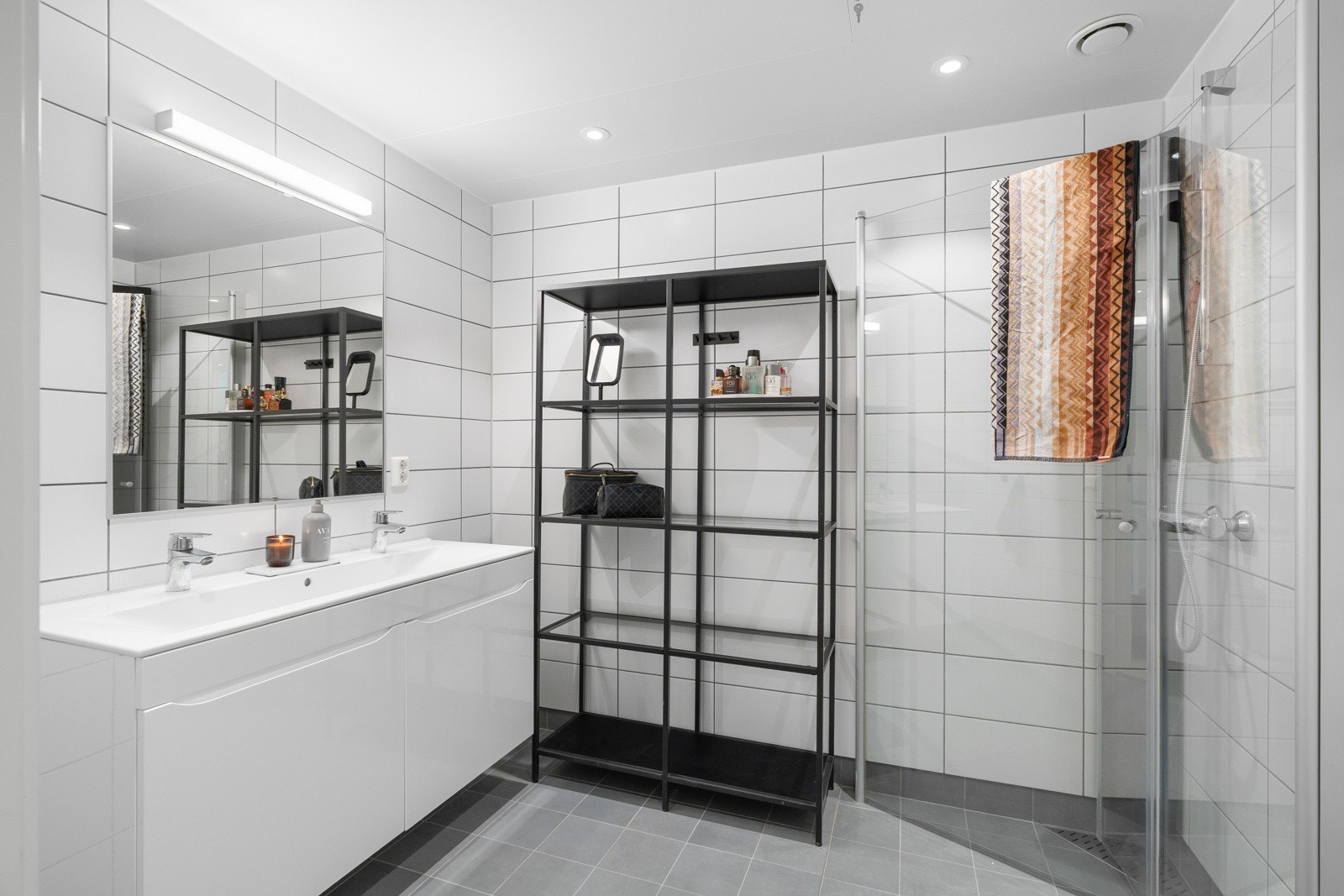 Lyst og pent bad med flislagte gulv og vegger. Badet er på 4,8 kvm og er utstyrt med dobbel servant, dusjnisje og har videre godt med plass for oppbevaring av toalettsaker og andre baderomsartikler. Galleribilde