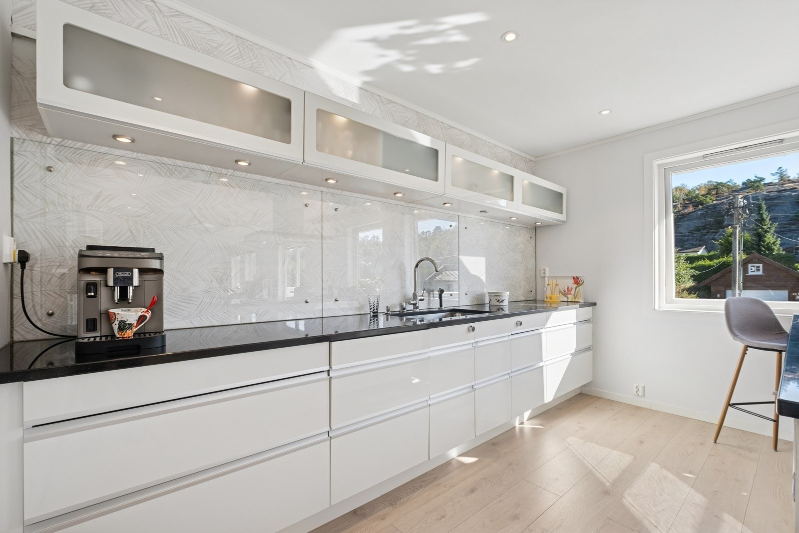 Innredning med hvite slette fronter og stein benkeplate med underlimt vask. Galleribilde