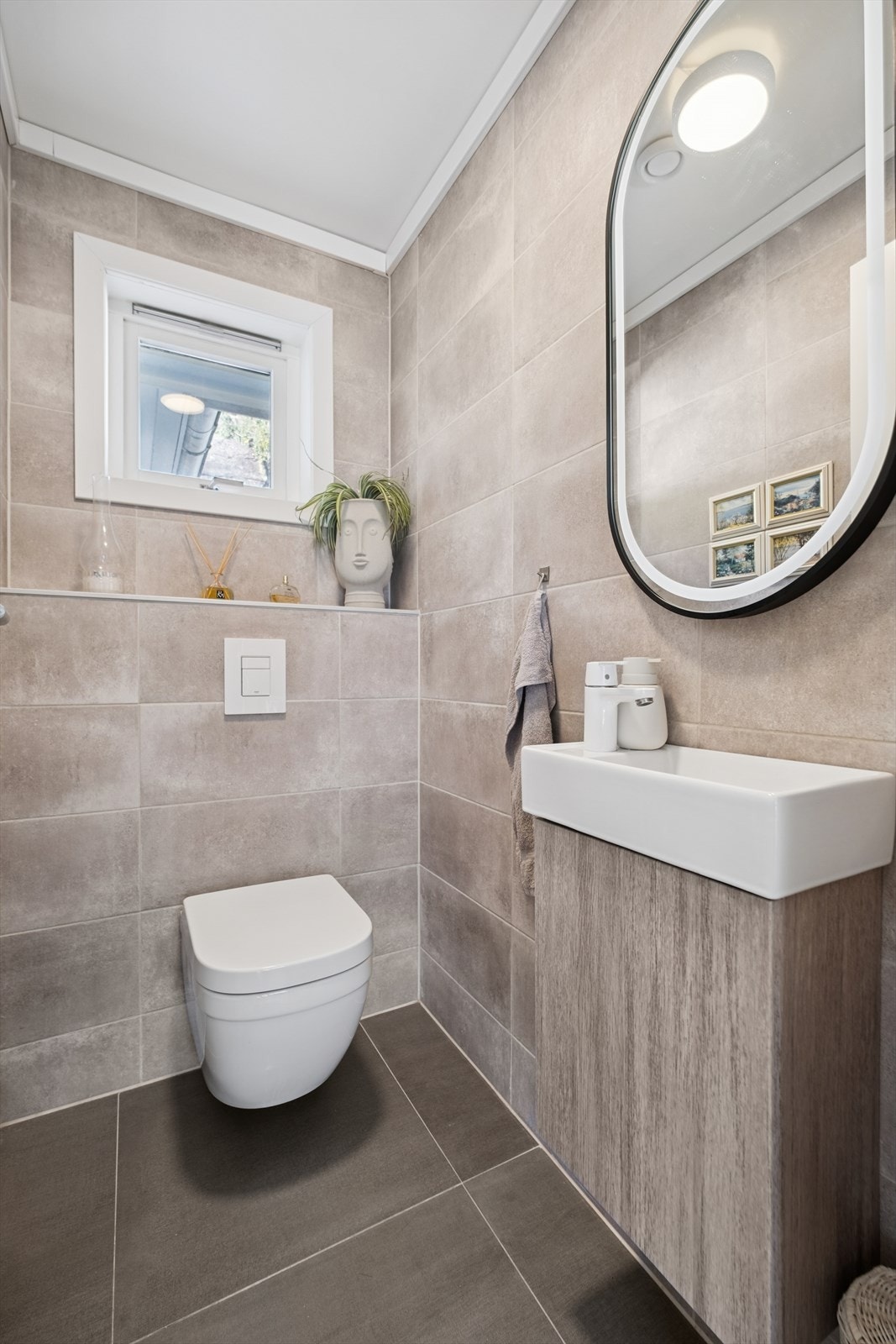 Toalettrommet er flislagt, utstyrt med vegghengt toalett, servant med skap og speil. Galleribilde