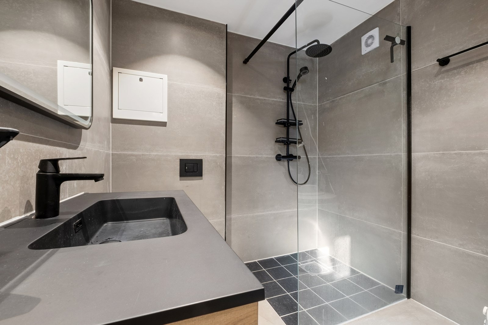 Badet er utstyrt med vegghengt toalett, dusjhjørne med glassvegg, innredning med servant og speil, samt opplegg for vaskemaskin. Galleribilde