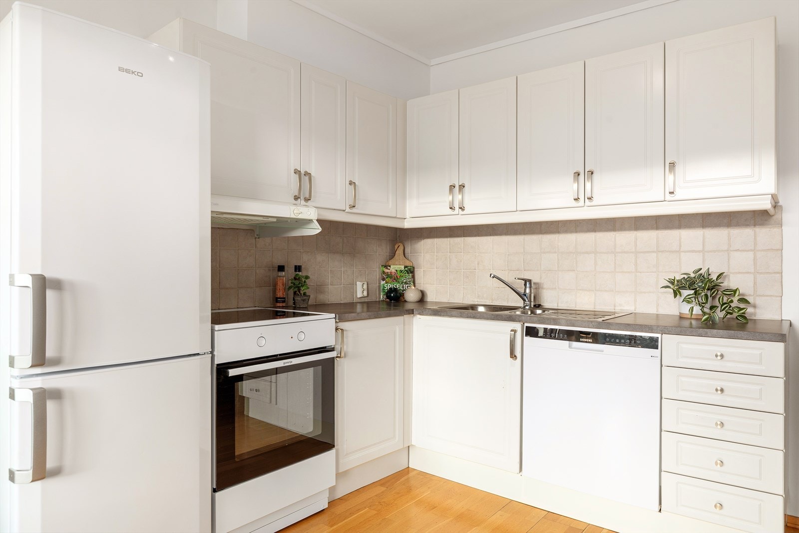 Her har du et godt utnyttet kjøkken, med profilerte fronter med flis over kjøkkenbenk, laminert benkeplate og frittstående hvitevarer (medfølger salget) Galleribilde