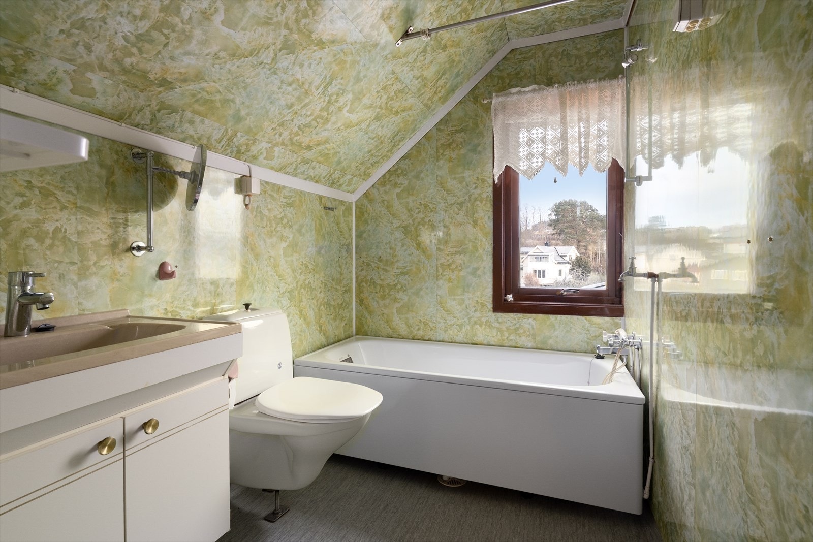 Badet i 2. etasje er også av eldre dato, med belegg på gulv og baderomsplater på vegger og i tak. Dette badet har innredning med skap og heldekkende servant, badekar og toalett. Varmes opp med stråleovn. Galleribilde