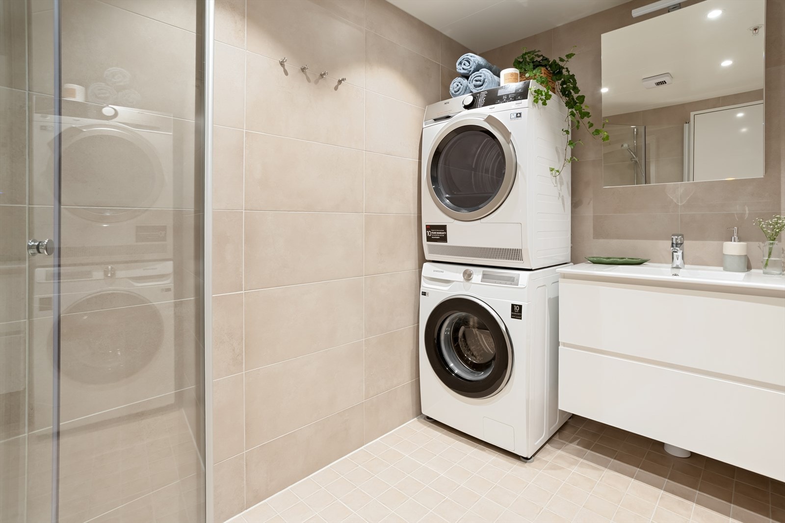 Badet er innredet med heldekkende servant med folierte fronter, speilskap, vegghengt toalett og et nedsenket dusjhjørne. Galleribilde