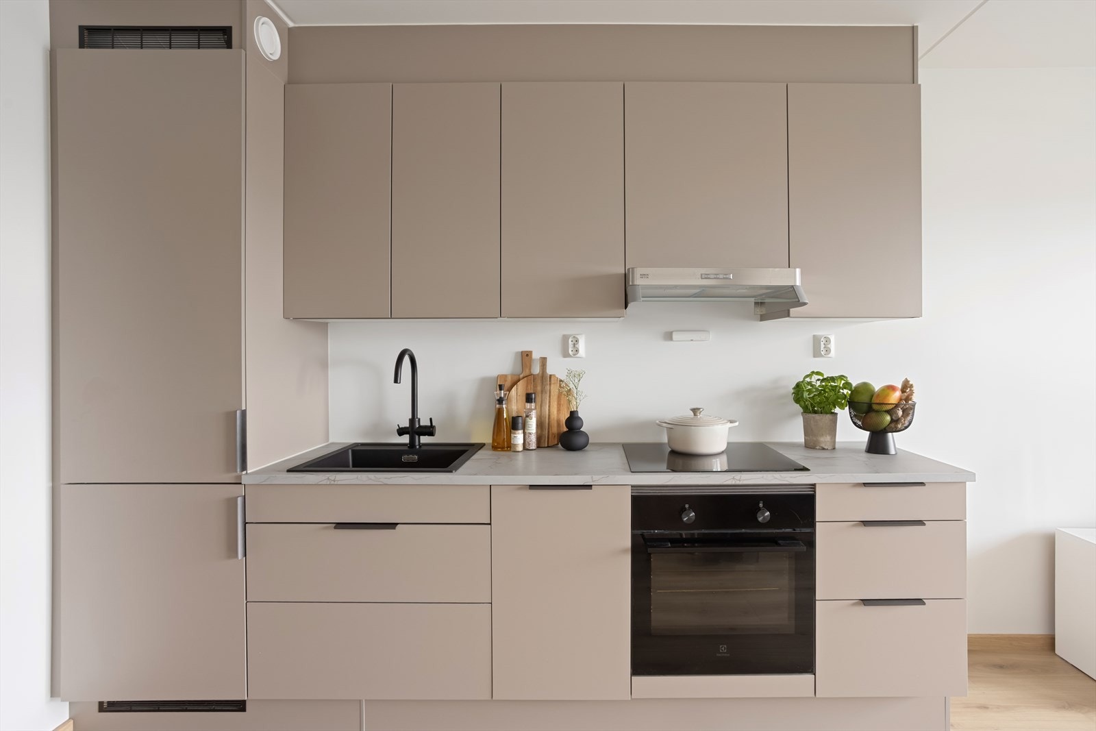 Kjøkkenet er innredet med glatte, folierte fronter og laminert benkeplate med nedfelt kum og komfyrvakt. Galleribilde